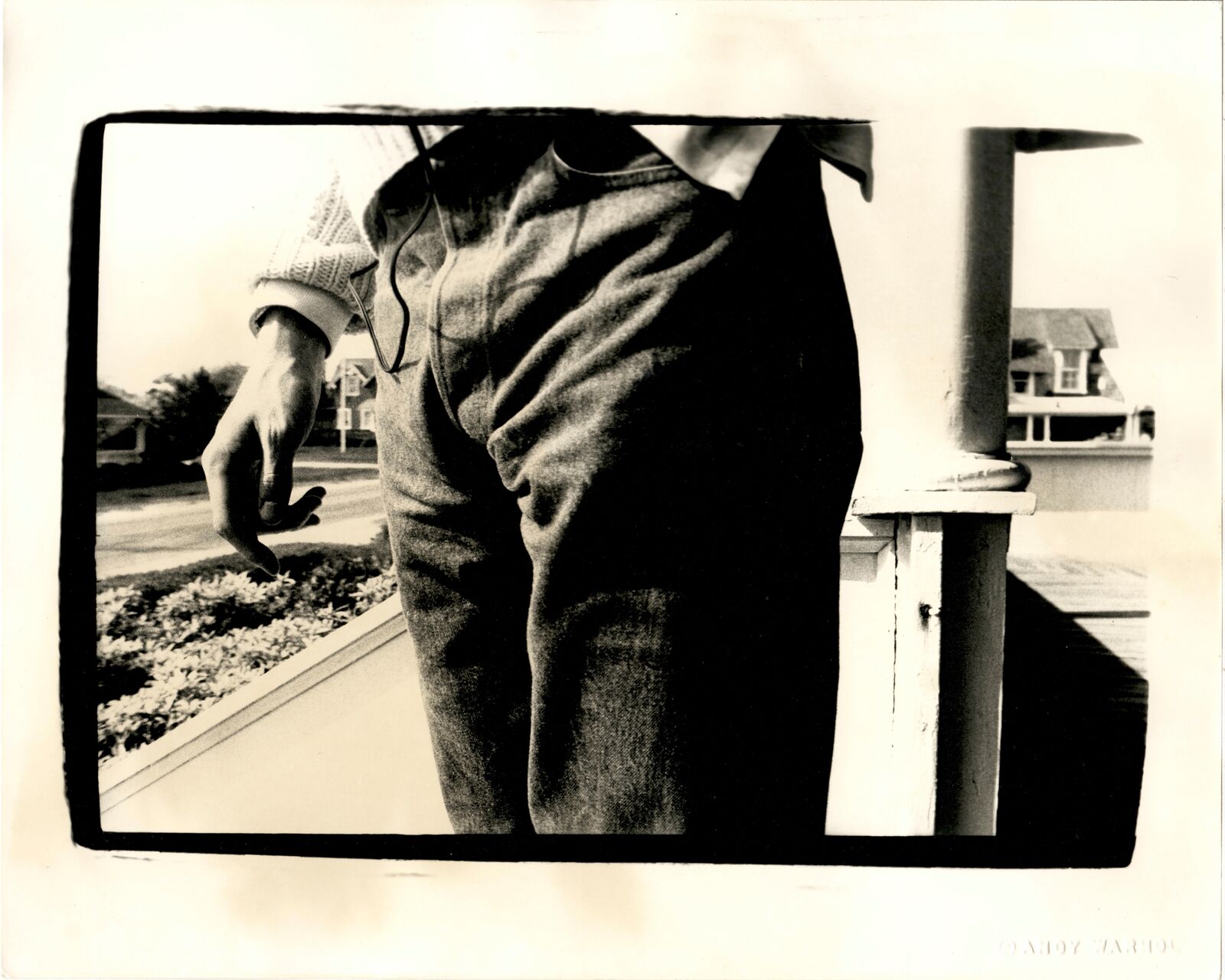 A black and white photo of a man standing on a porch.