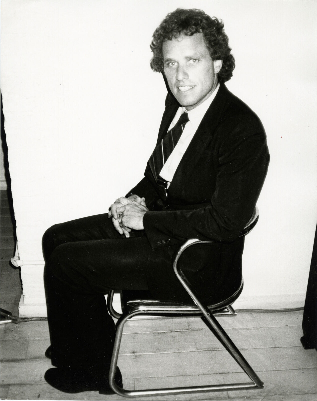 A man in a suit and tie sitting on a chair.