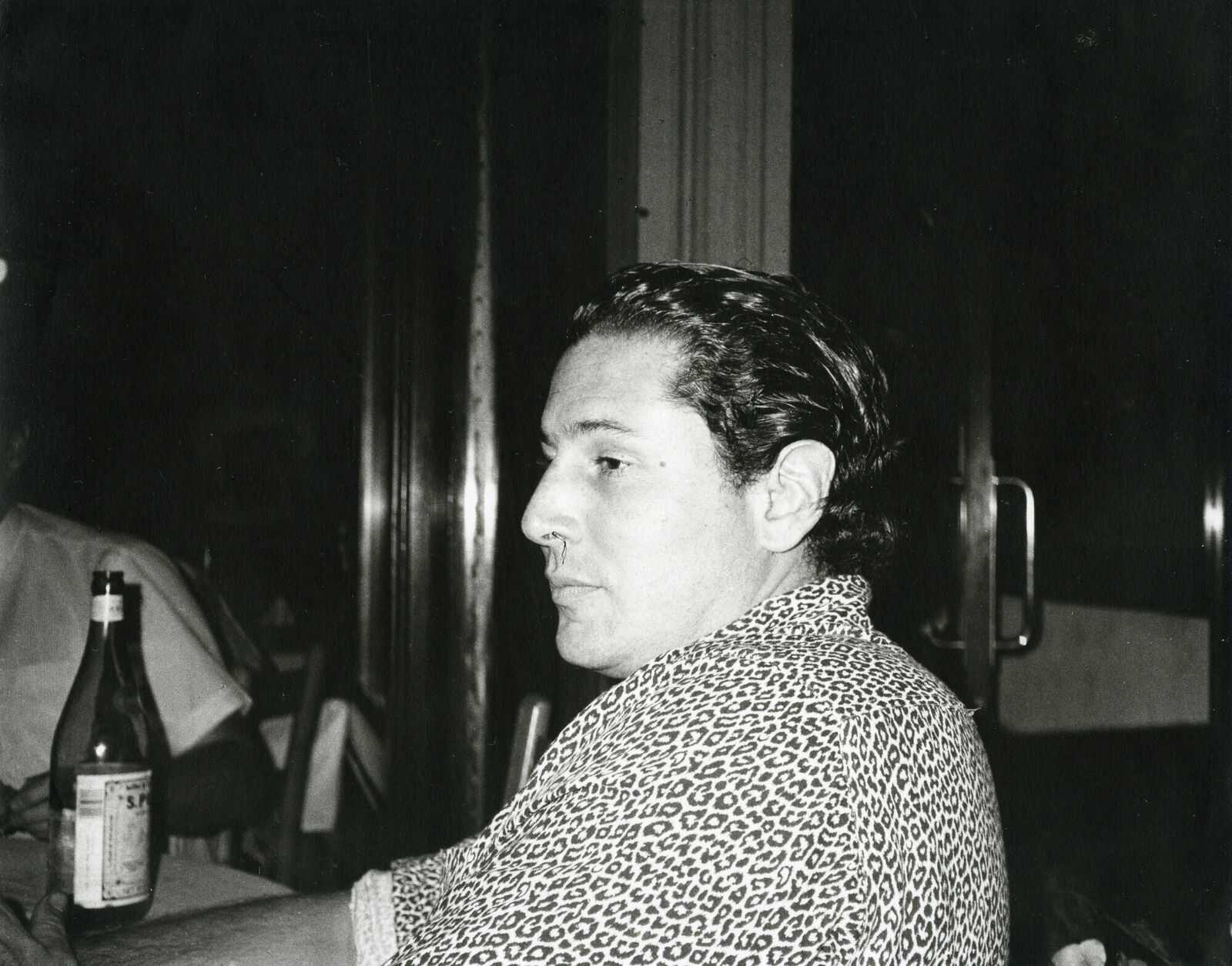 A man sitting at a table with a bottle of wine.