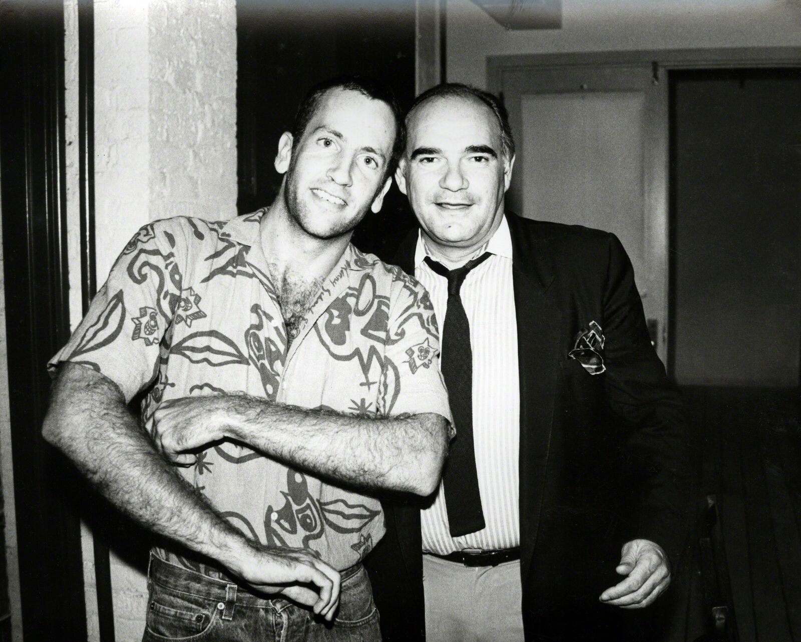 A man standing next to a man in a shirt and tie.