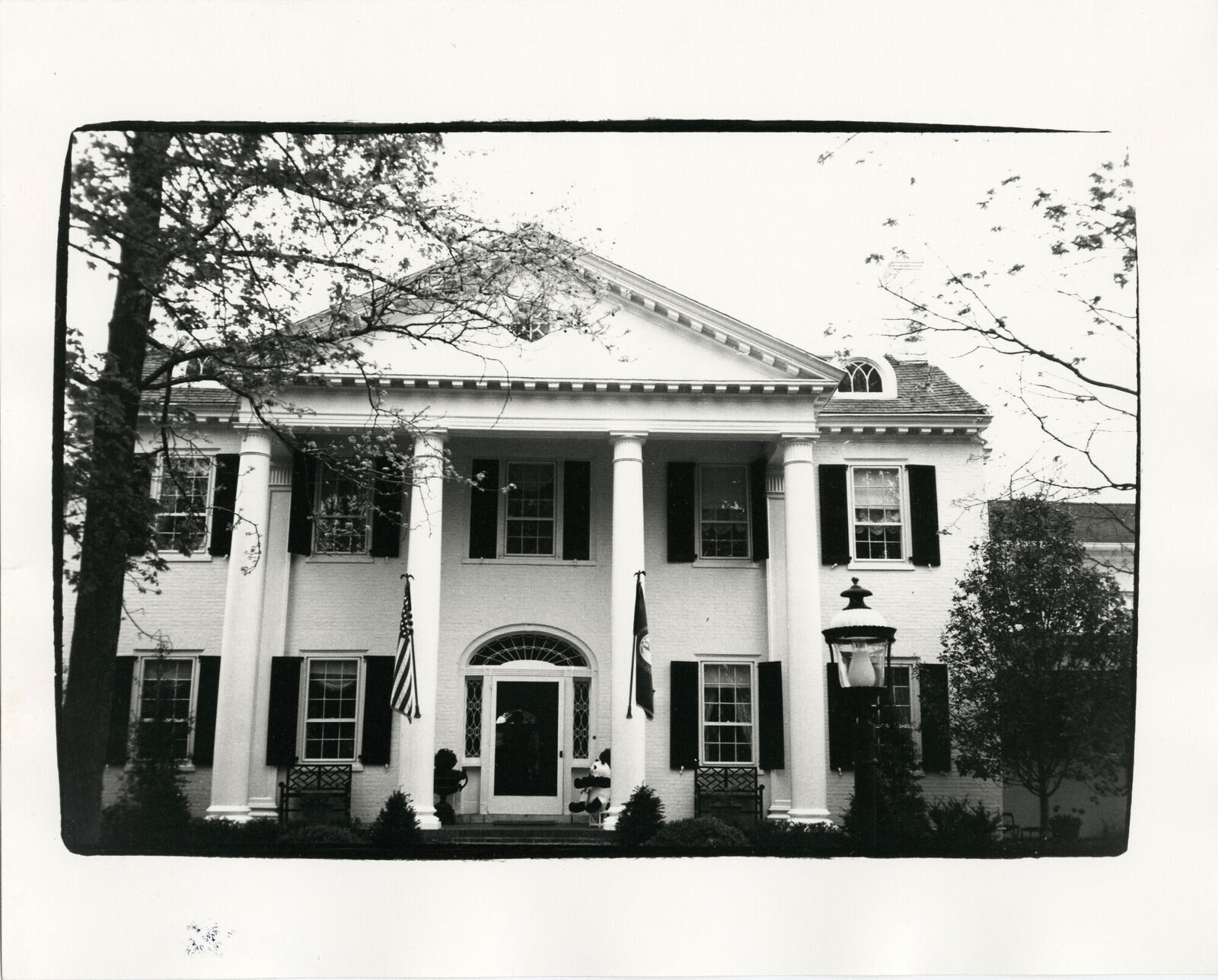 A black and white photo of a large white house.