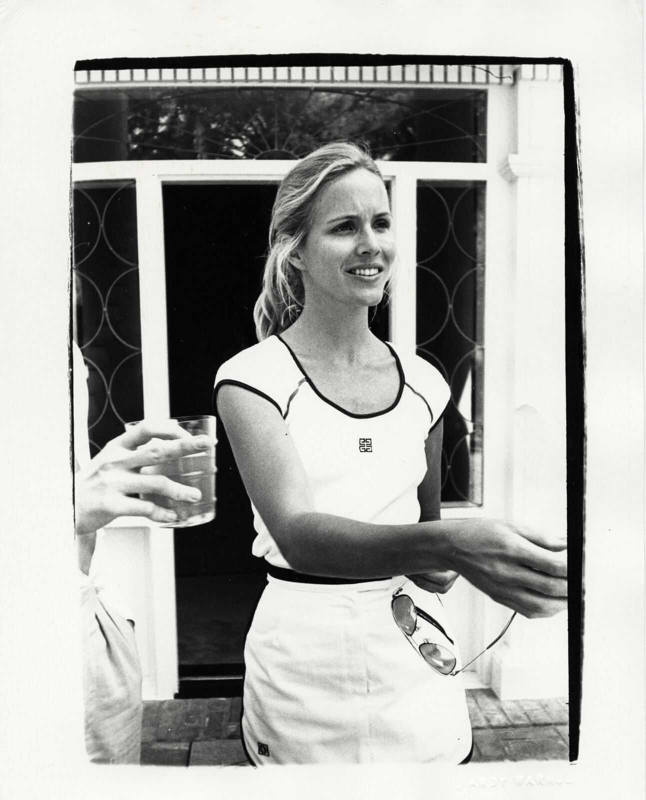 A black and white photo of a woman holding a glass of water.