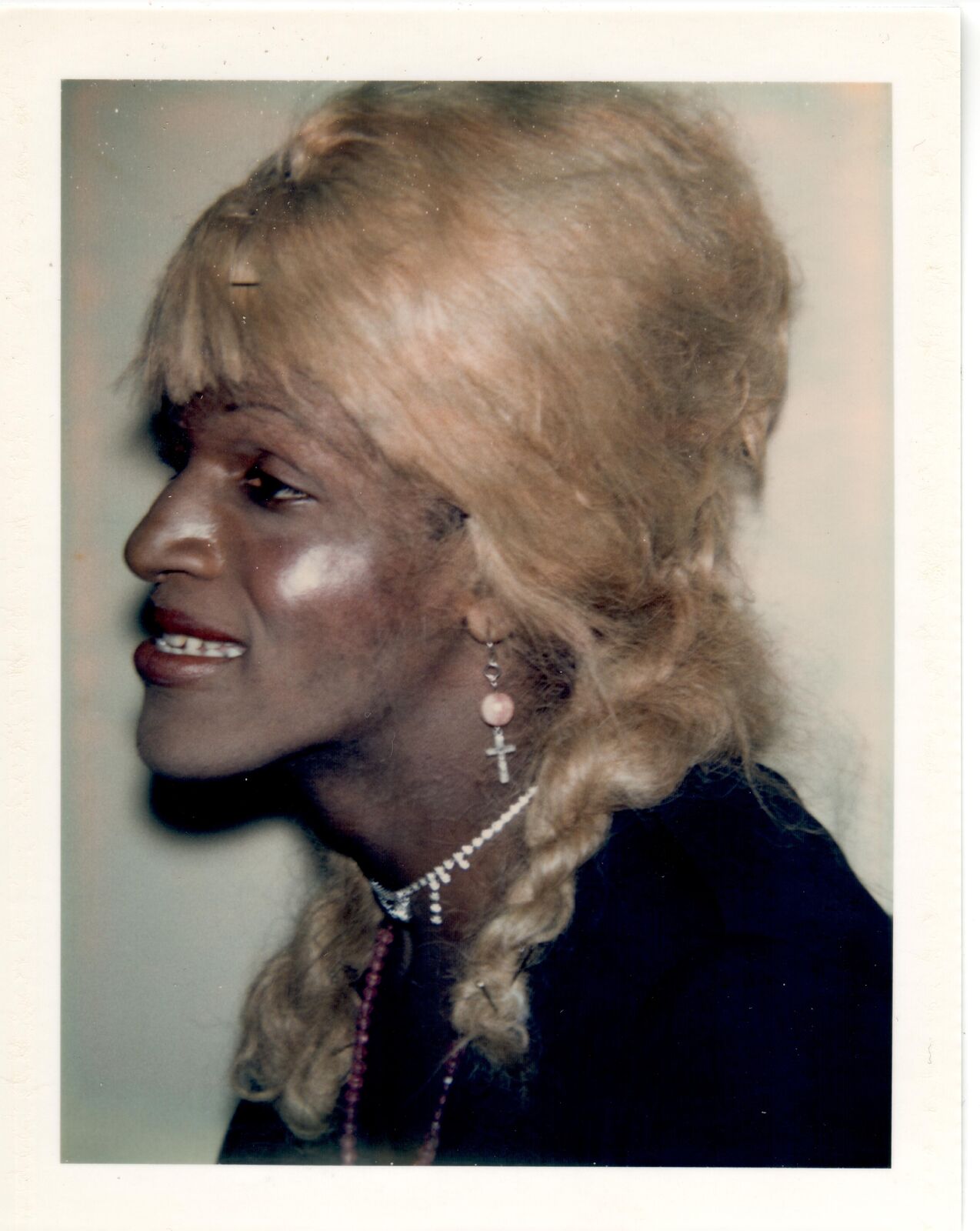 A woman with blonde hair wearing a necklace and earrings.