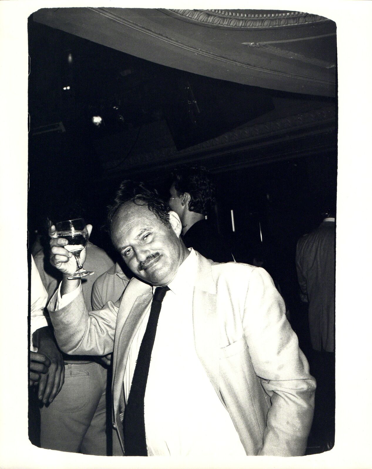 A man in a suit and tie holding a glass of wine.