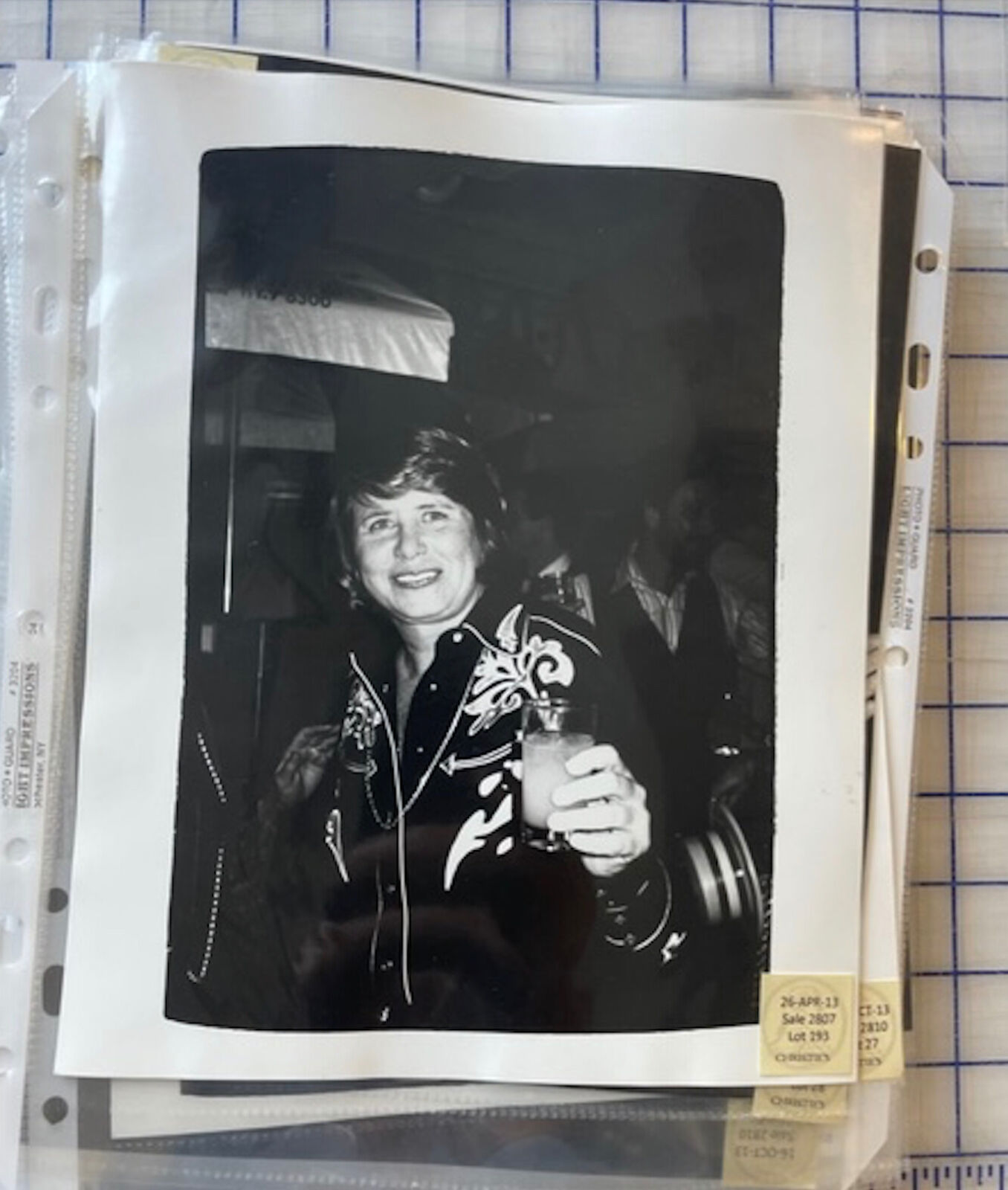 A black and white photo of a woman holding a drink.