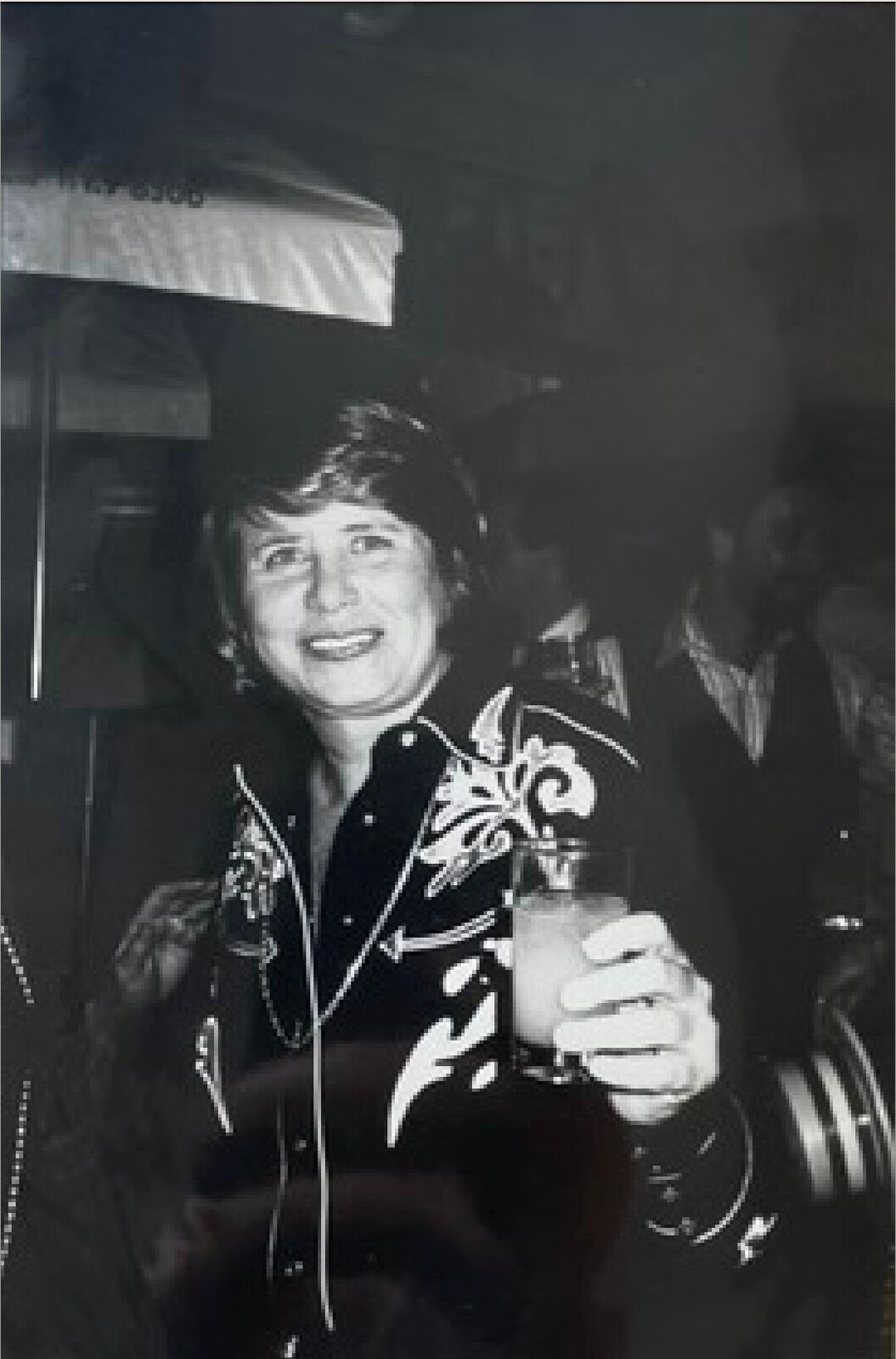 A black and white photo of a woman holding a drink.