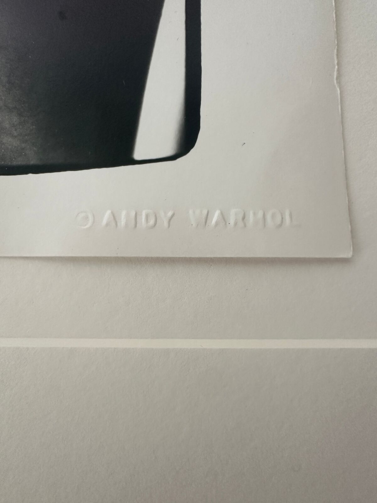 A shirtless man in a black underwear leaning against a wall.