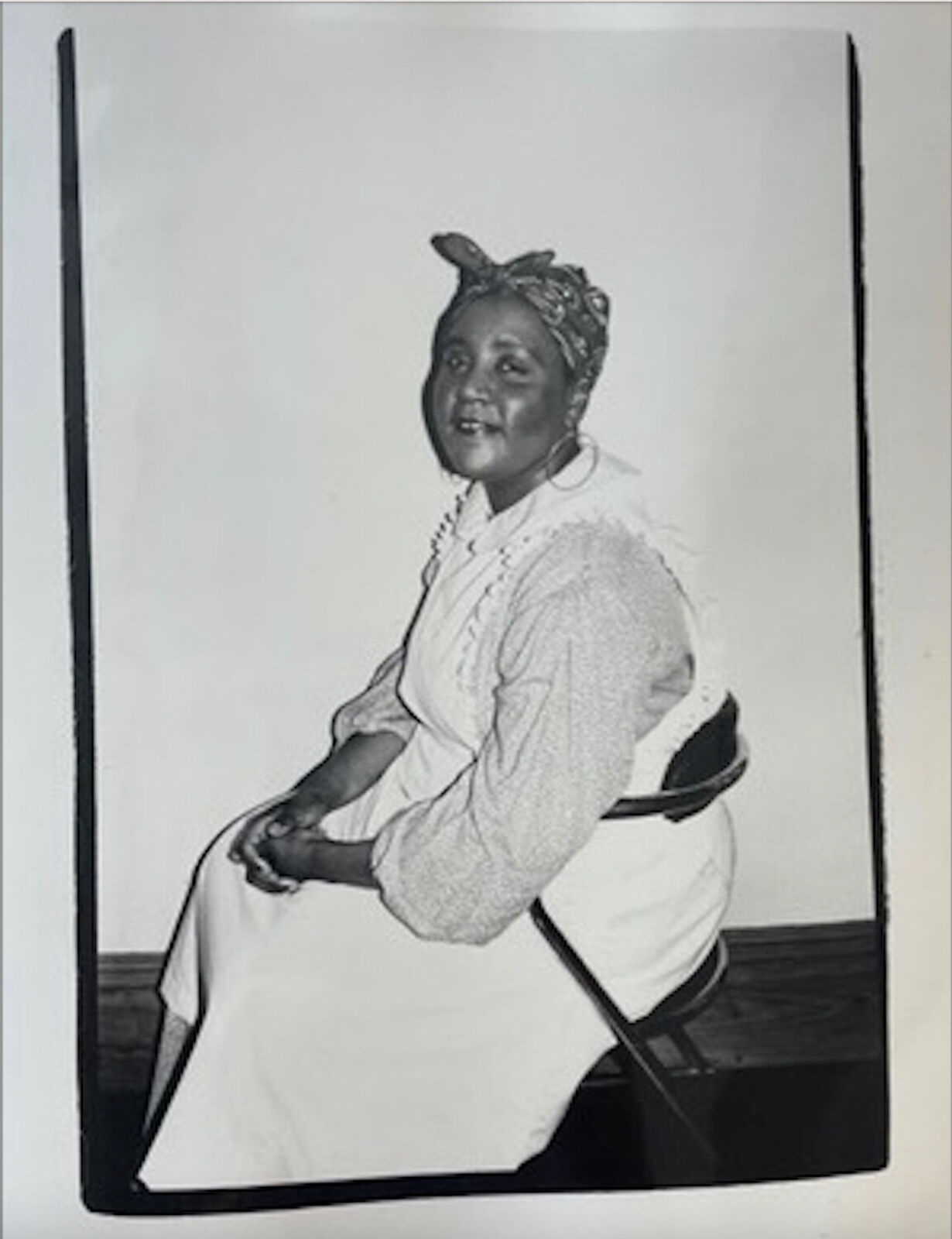 A black and white photo of a woman sitting on a chair.