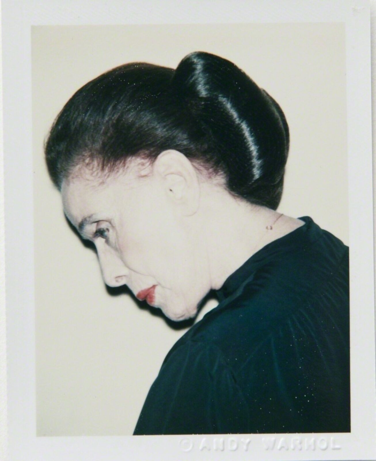 A polaroid photo of a woman with her hair in a bun.