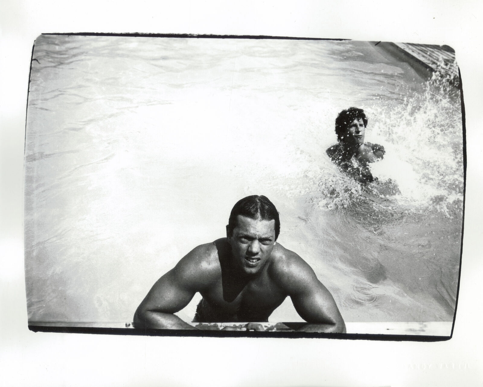 A black and white photo of a man swimming in a pool.