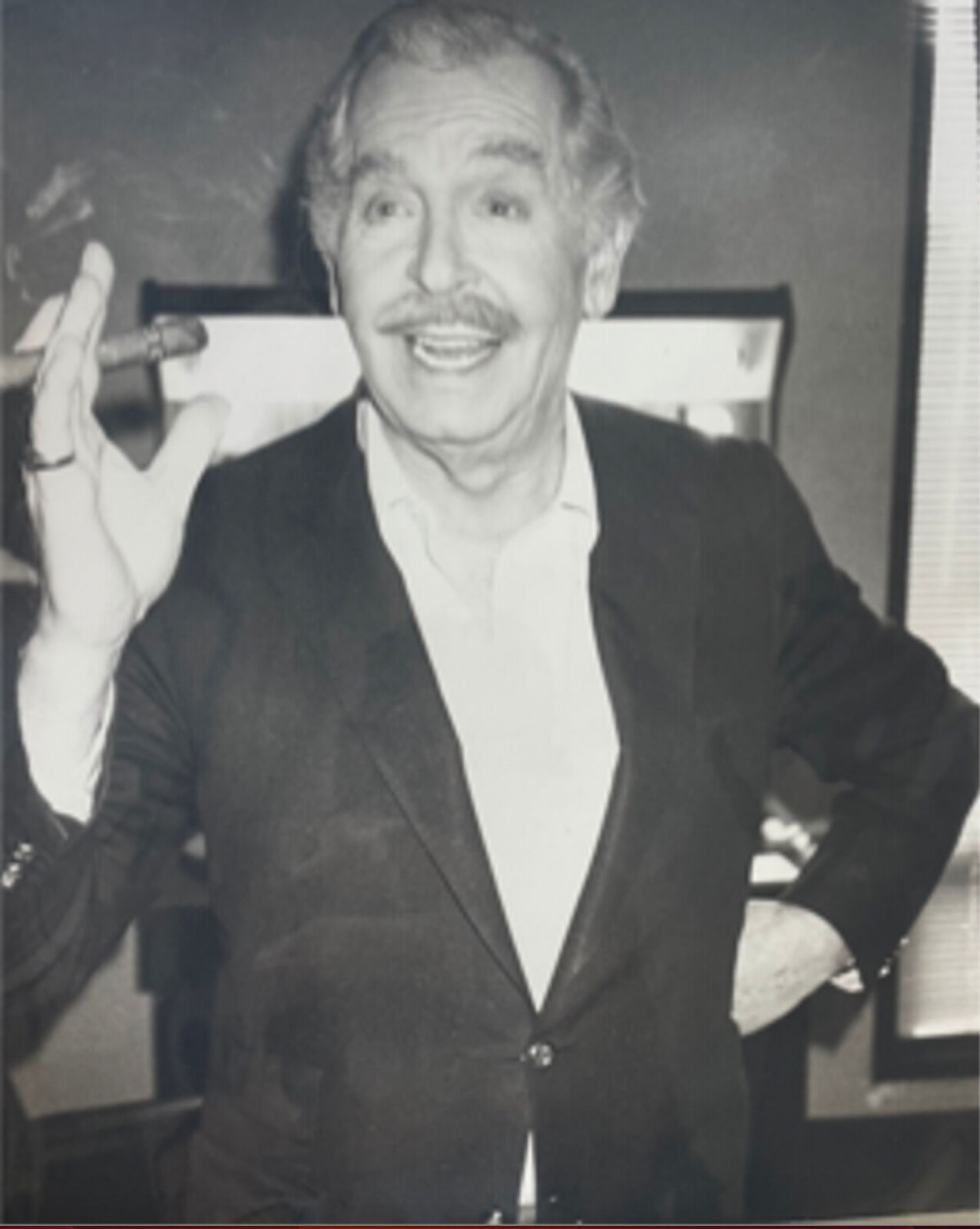A black and white photo of a man in a suit smoking a cigar.