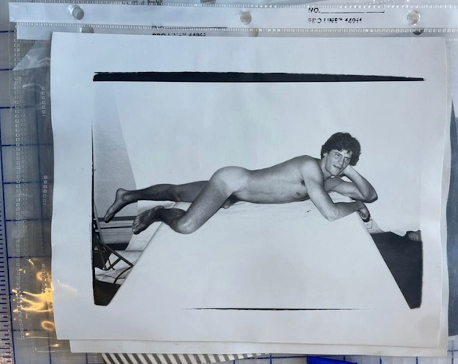 A black and white photo of a naked man laying on a table.