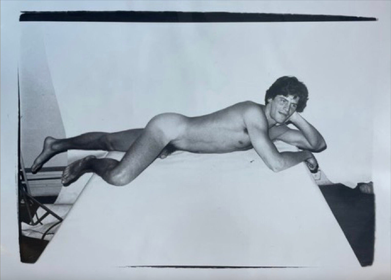 A black and white photo of a naked man laying on a table.