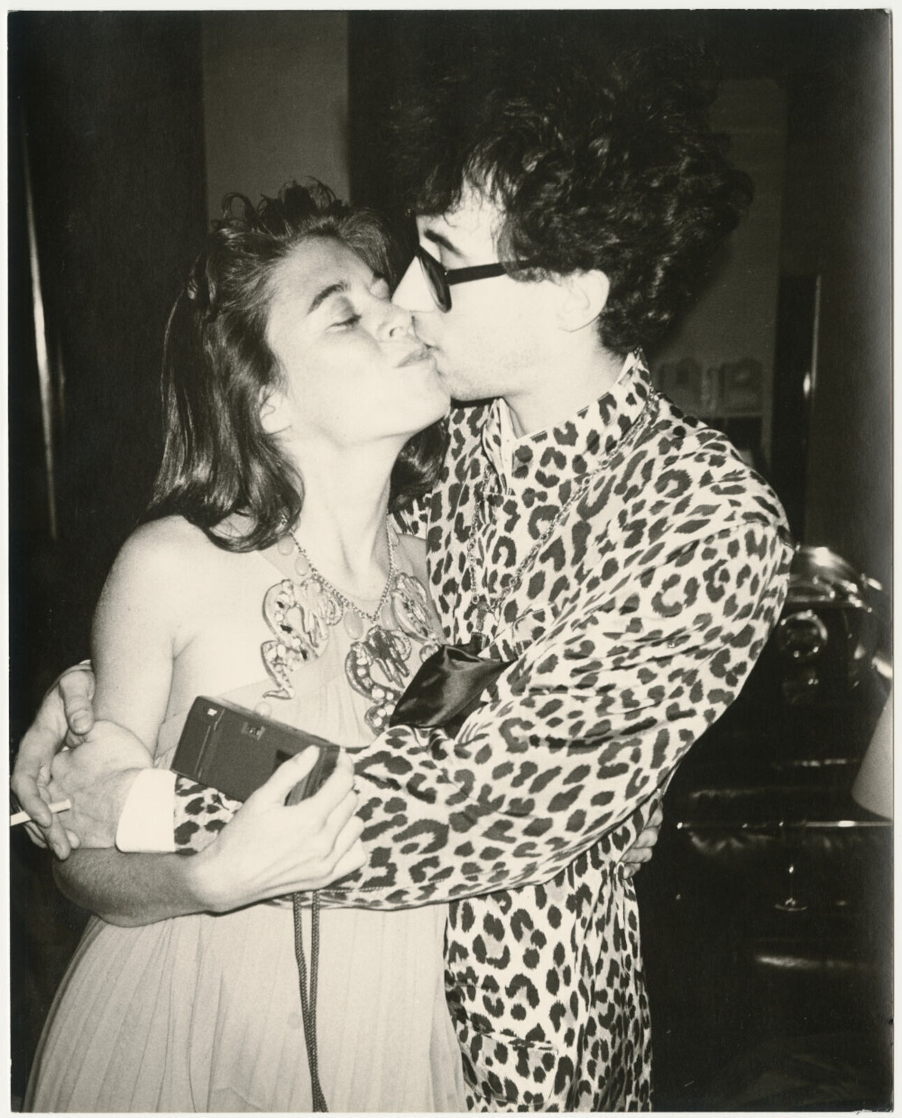 A man and a woman are kissing in a room.