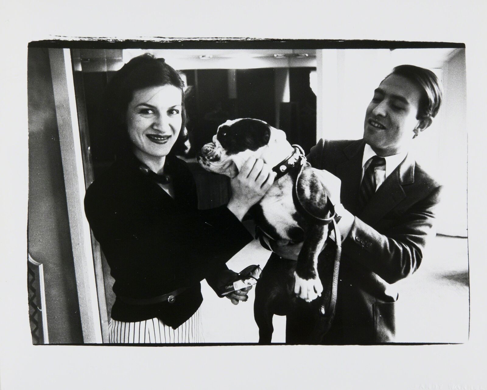 A man and woman holding a dog in their arms.