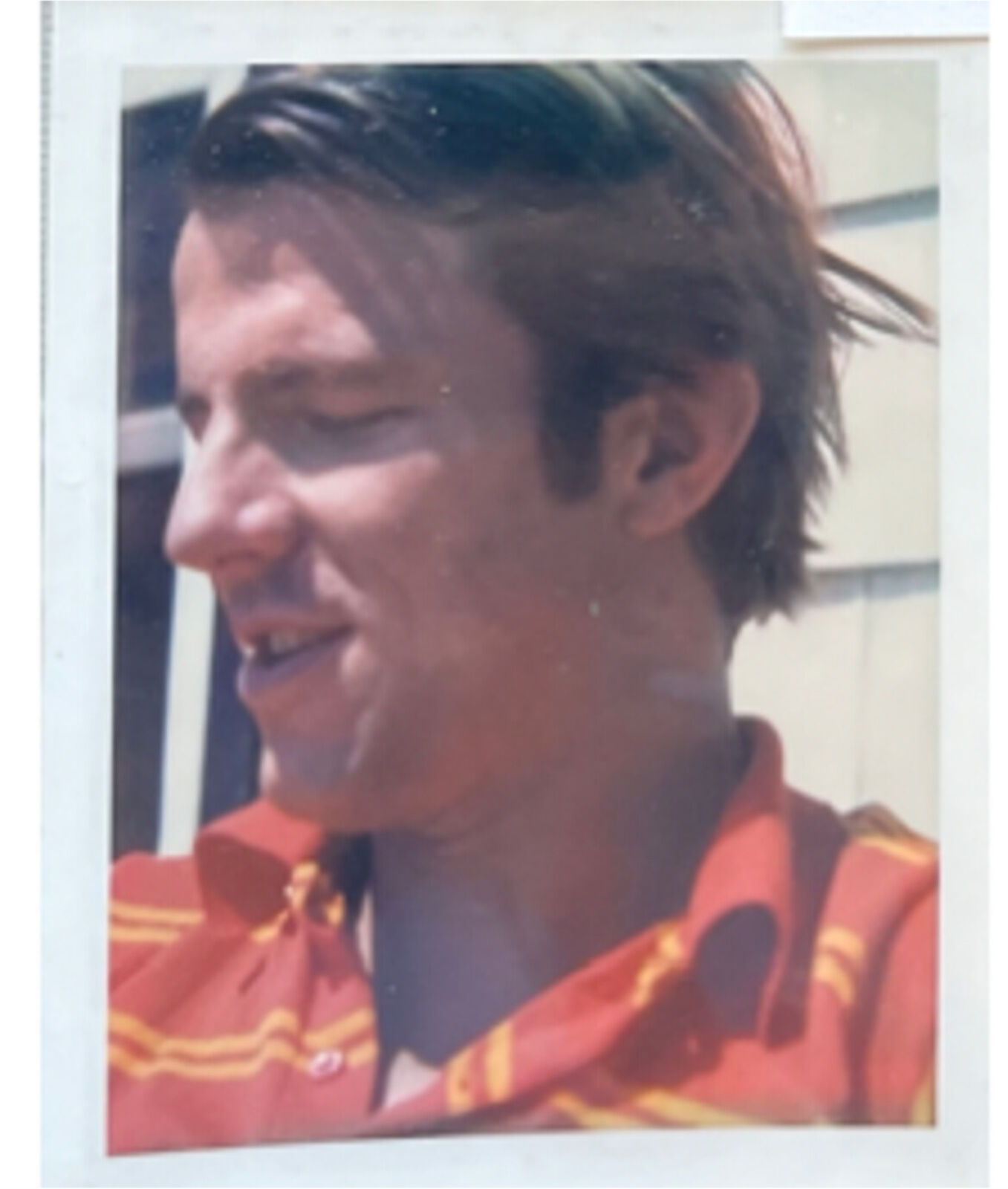 A man in a red and yellow striped shirt smiles at the camera.