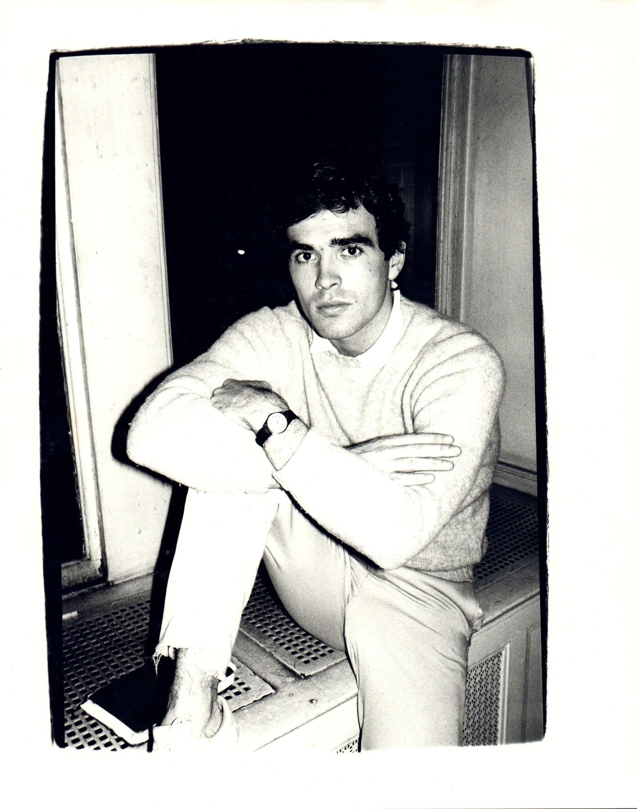 A black and white photo of a man sitting on a bench.