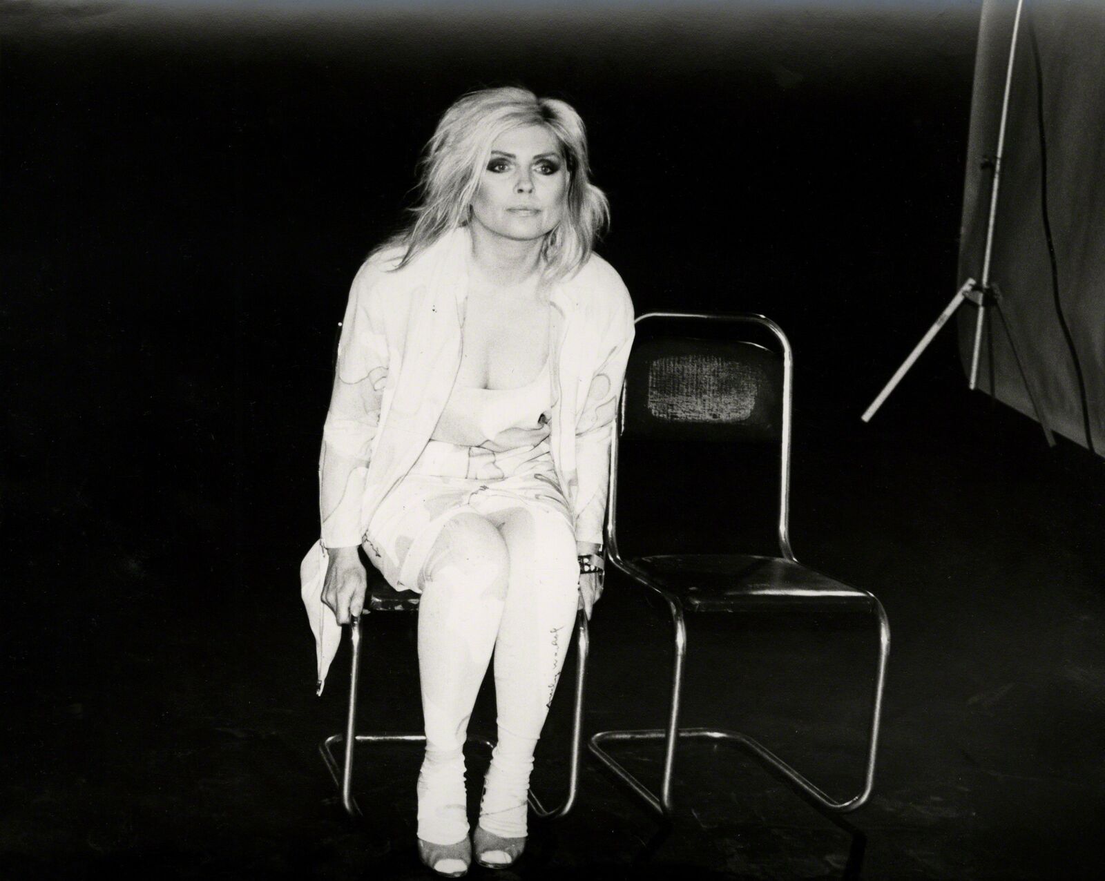 A woman sitting on a chair in front of a camera.