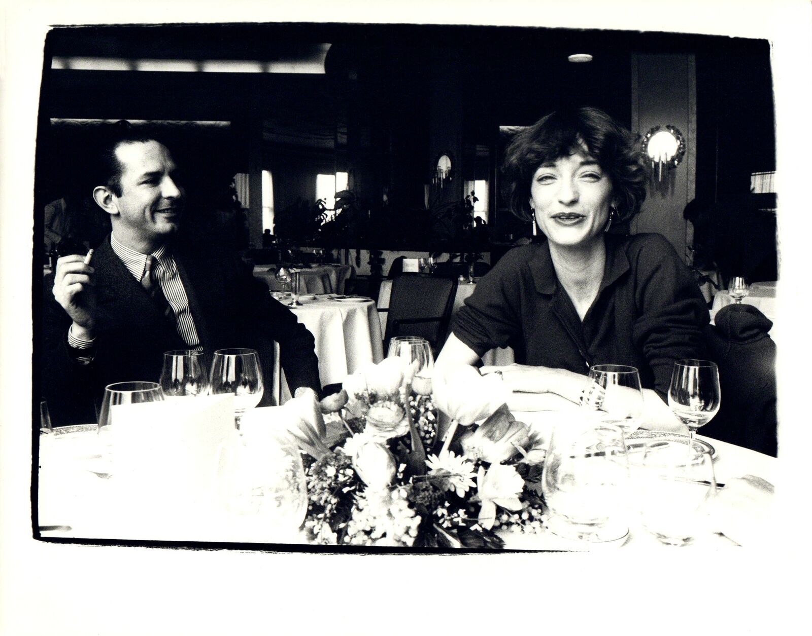 A man and a woman sitting at a table with wine glasses.