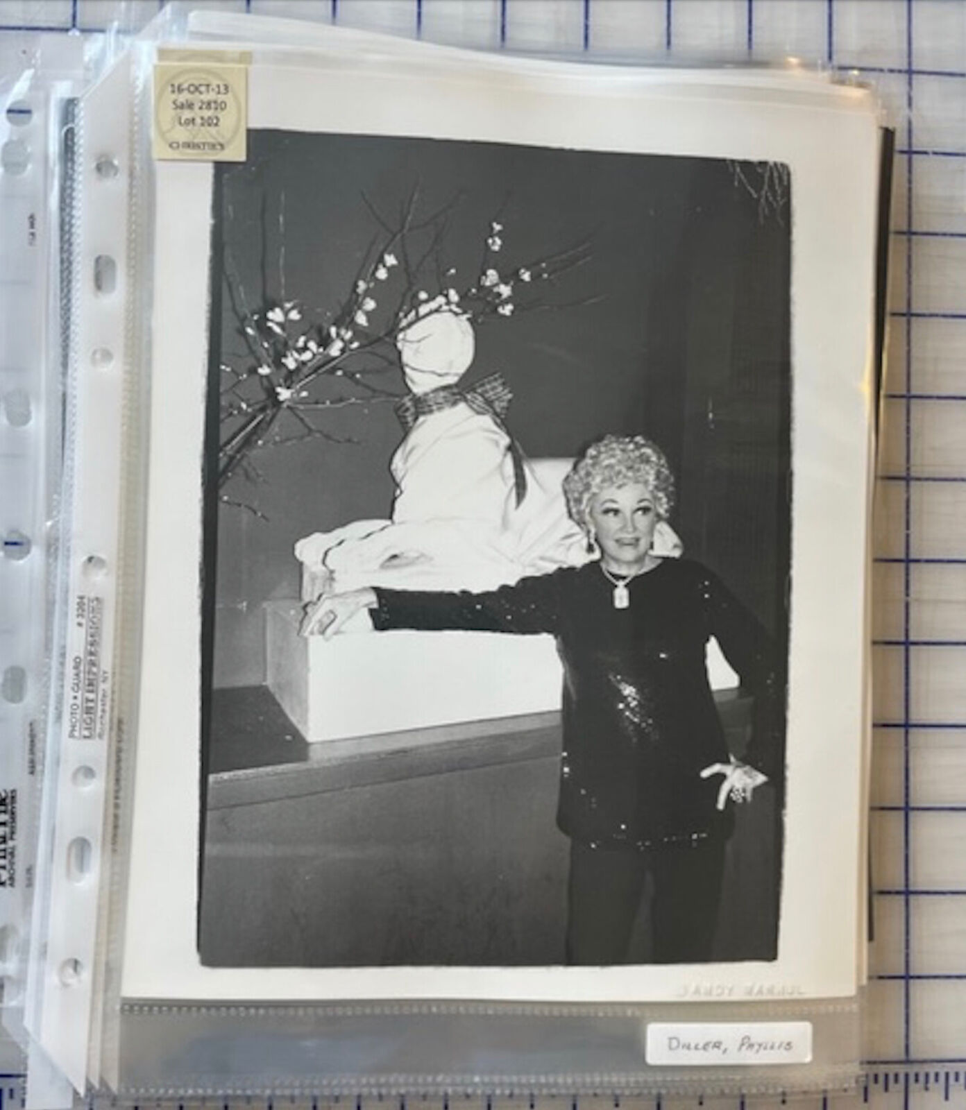 A black and white photo of a woman standing next to a snowman.