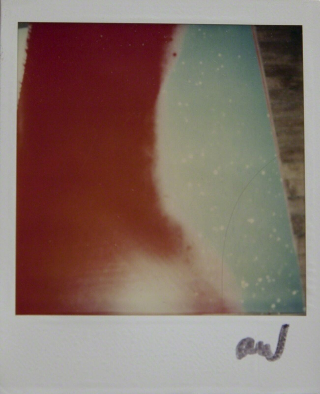 A polaroid photo of a red and green painting on a wall.