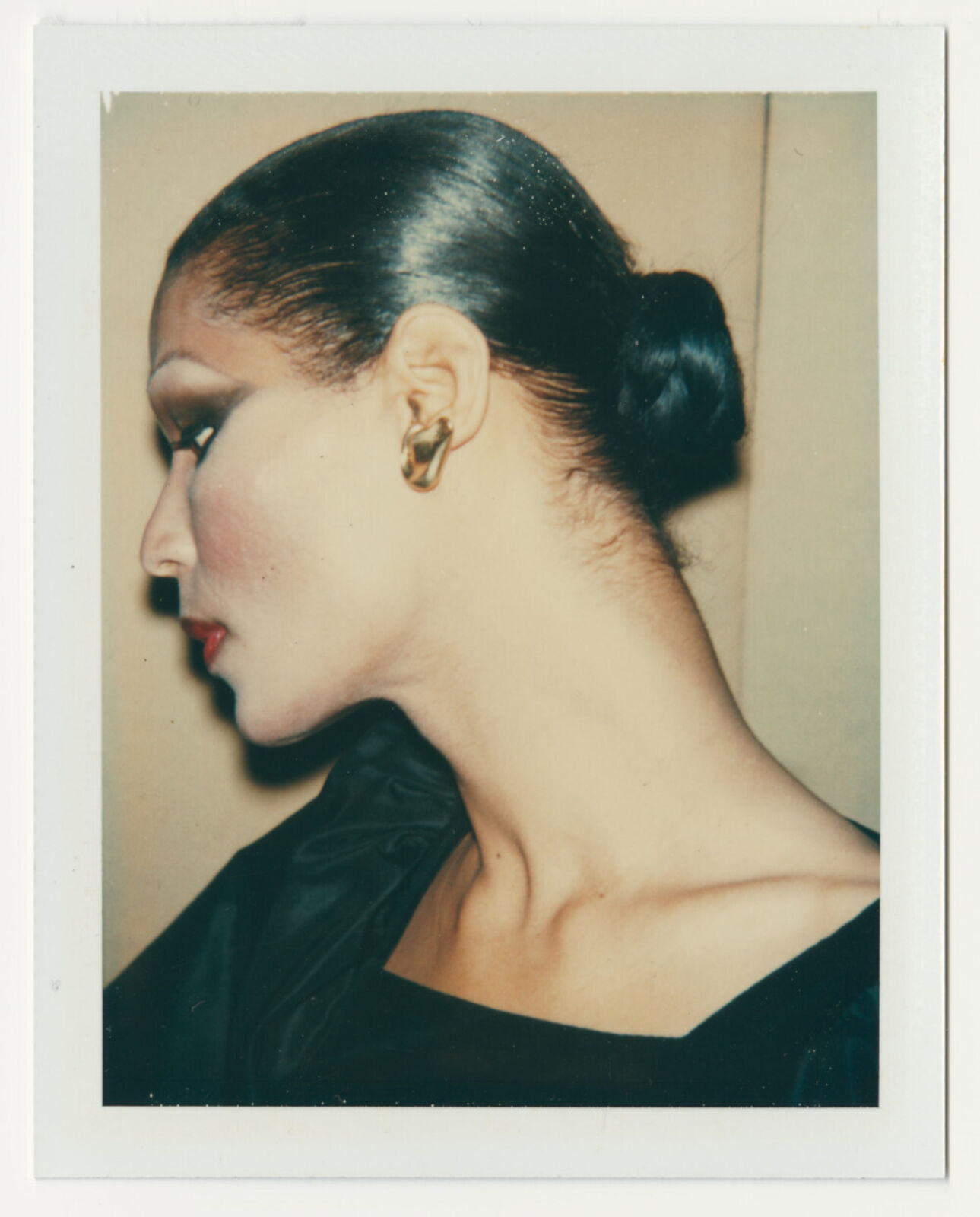 A woman with a black dress and gold earrings in her hair.