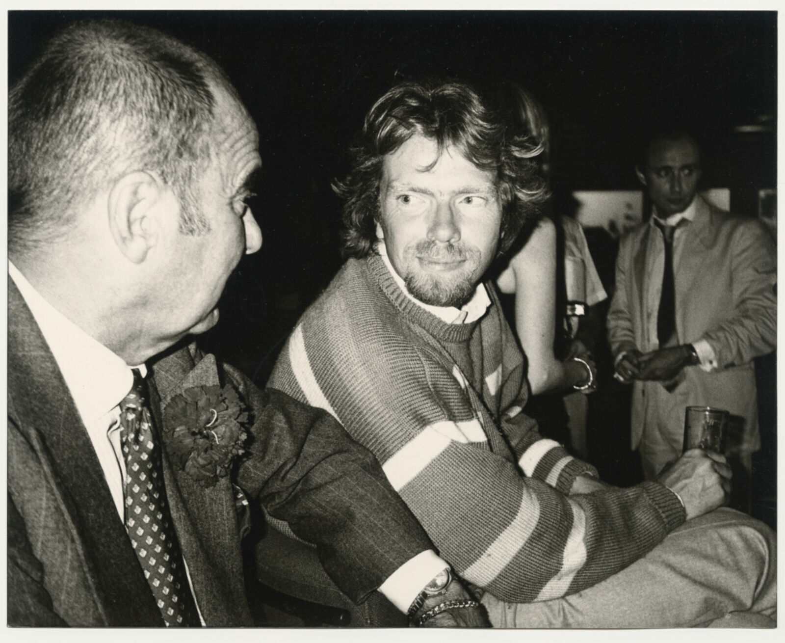 A black and white photo of two men sitting next to each other.