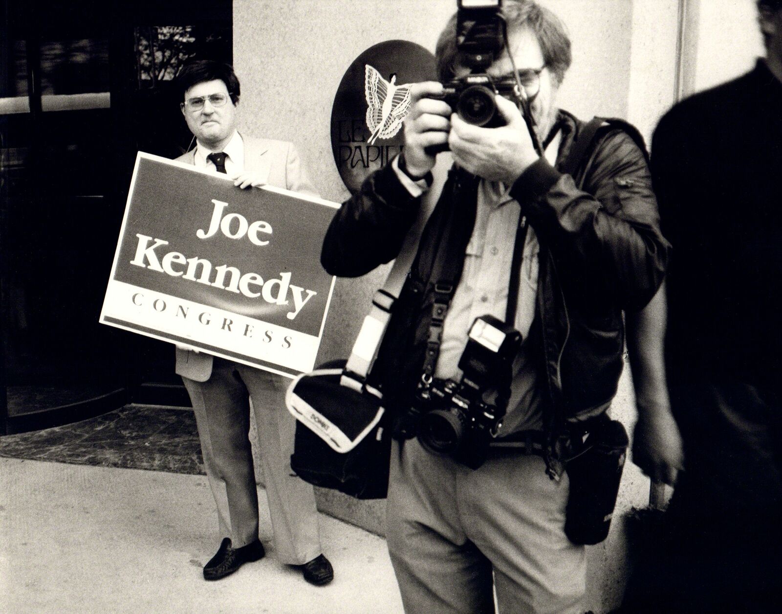 A man taking a picture of a man holding a sign.