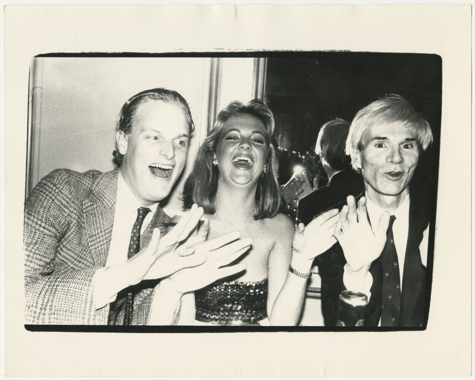 A black and white photo of two men and a woman clapping.