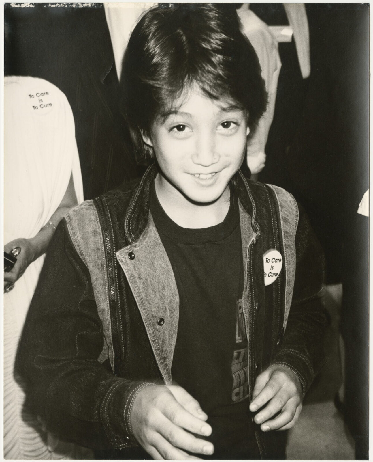 A young boy in a black and white photo with a badge on his jacket.