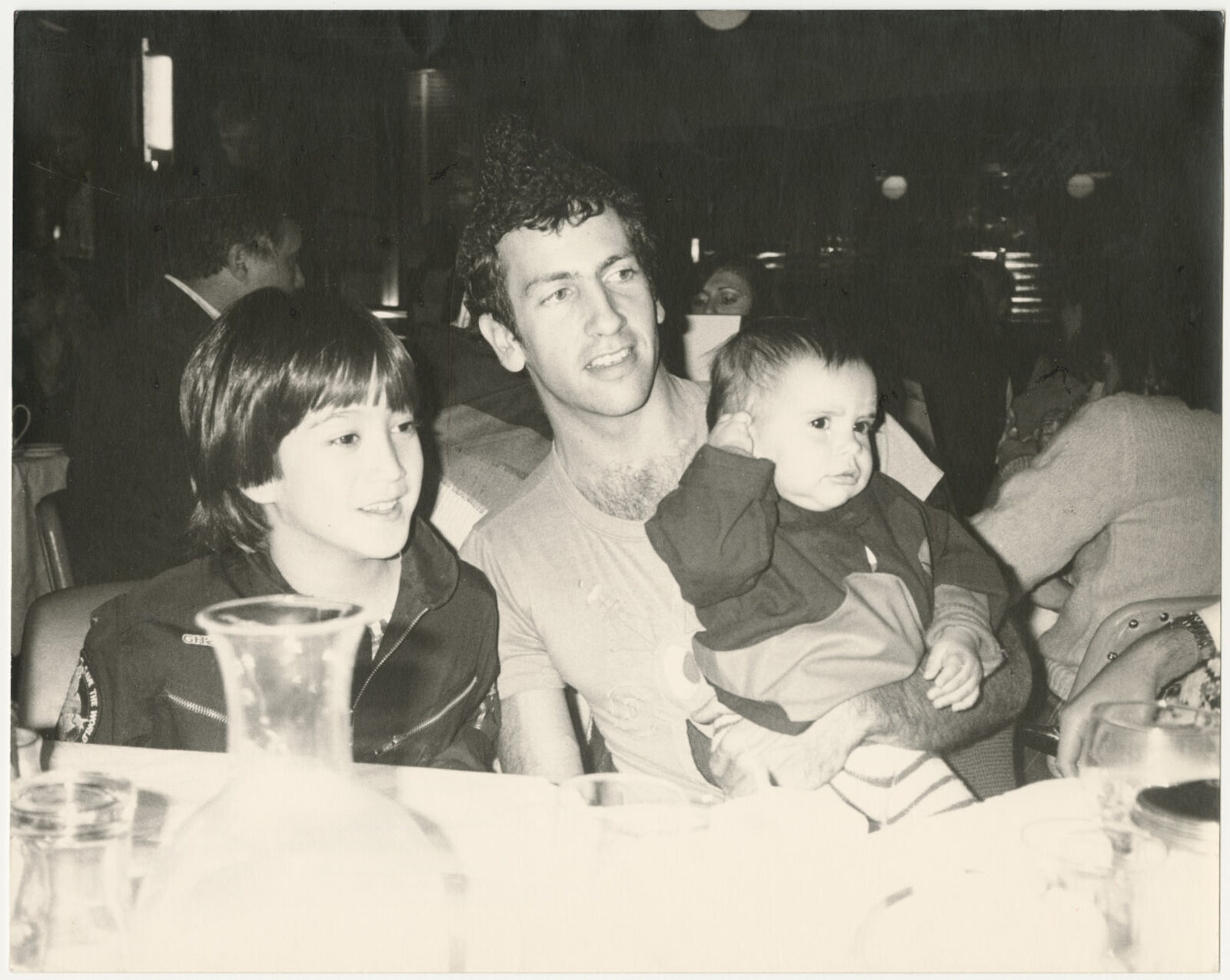 A man holding a baby while sitting next to two young boys.