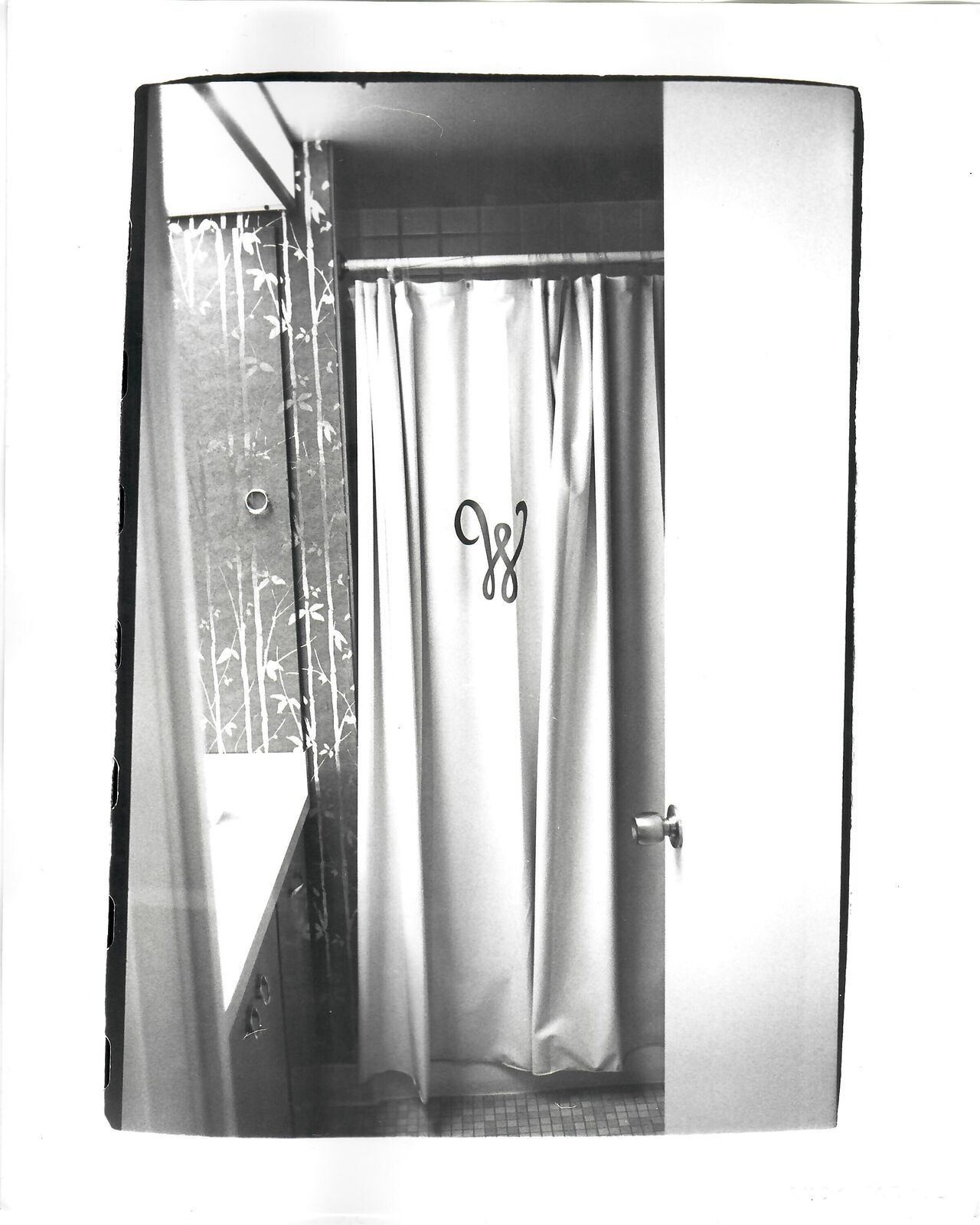 A black and white photo of a bathroom with a shower curtain.