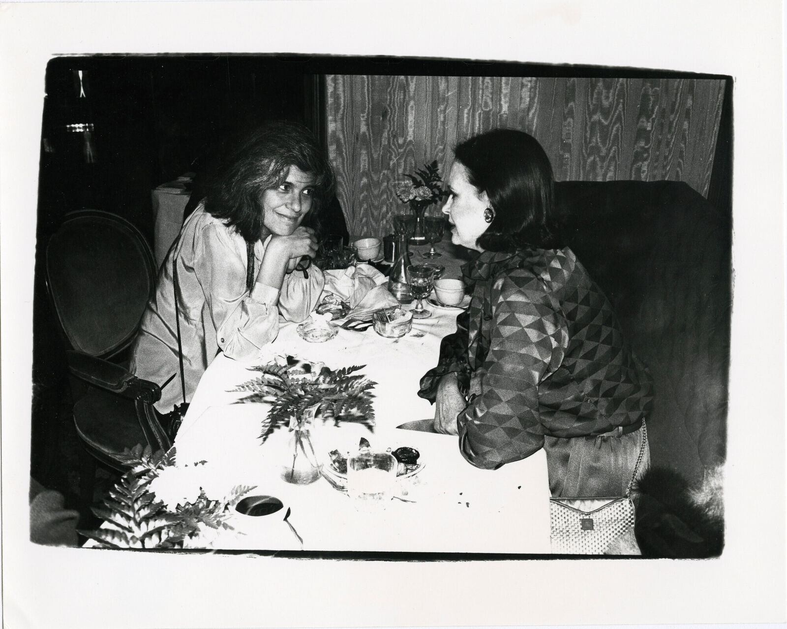 Two women sitting at a table talking to each other.