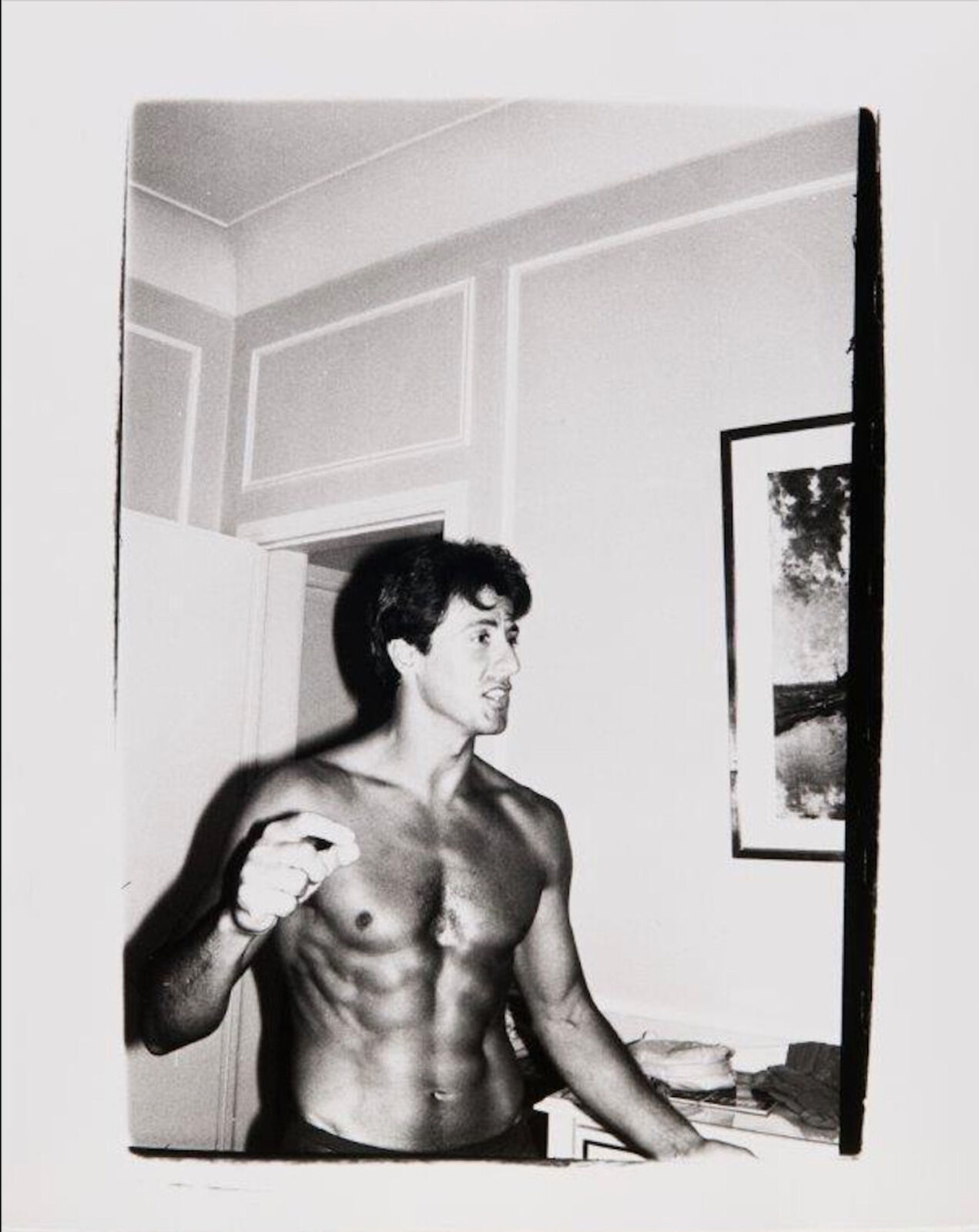 A shirtless man standing in front of a mirror.