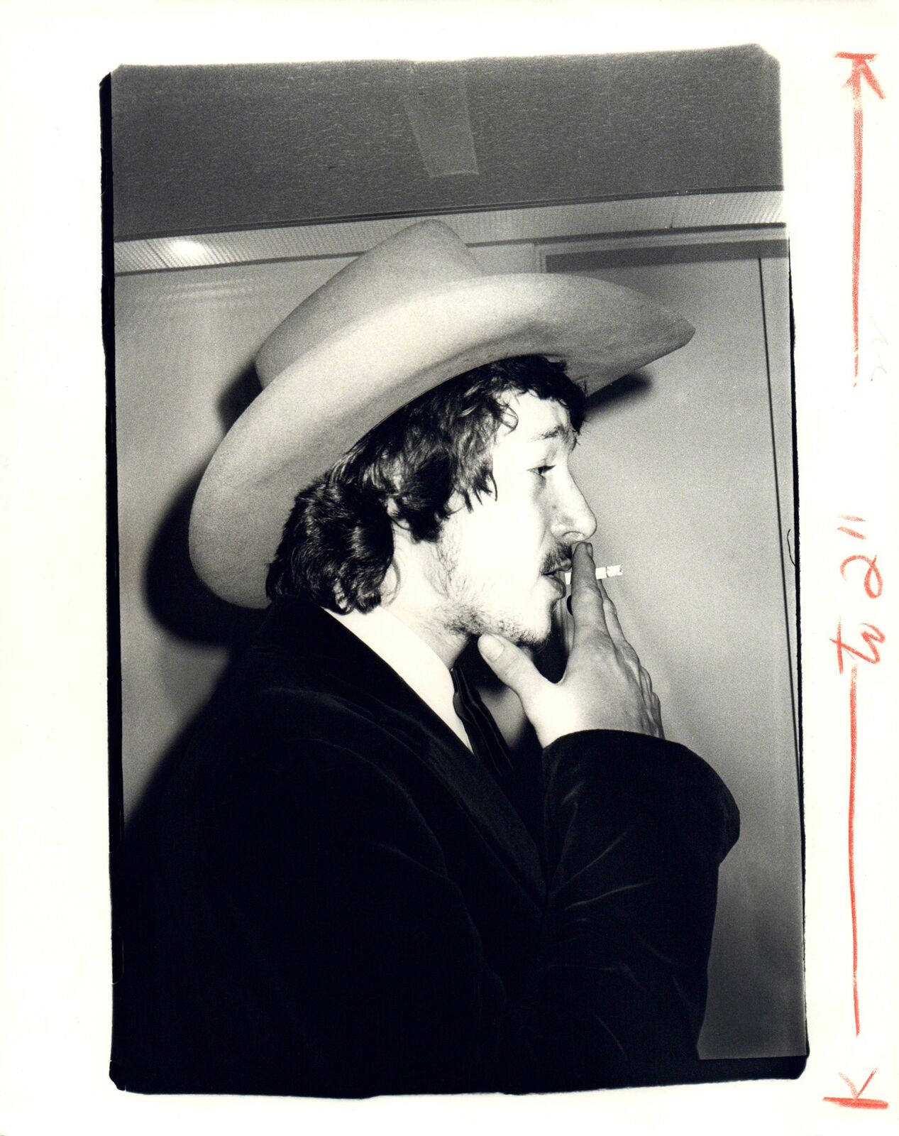 A black and white photo of a man in a cowboy hat smoking a cigarette.