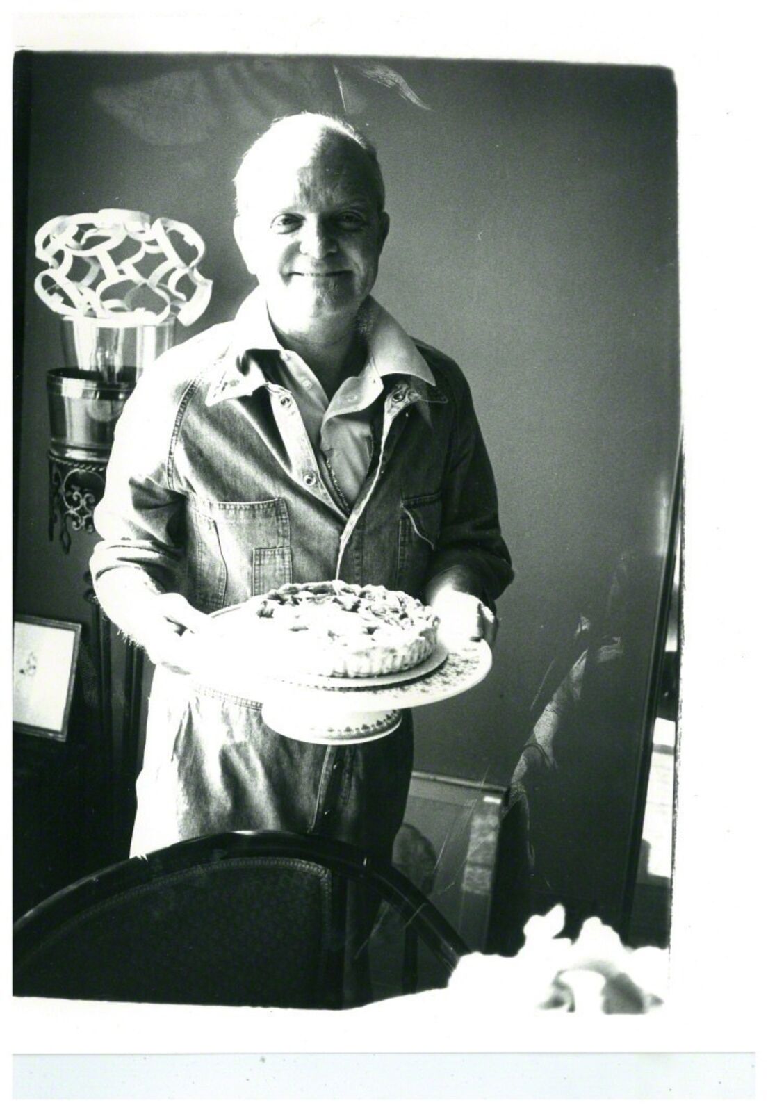 A man holding a pie on a plate in his hands.