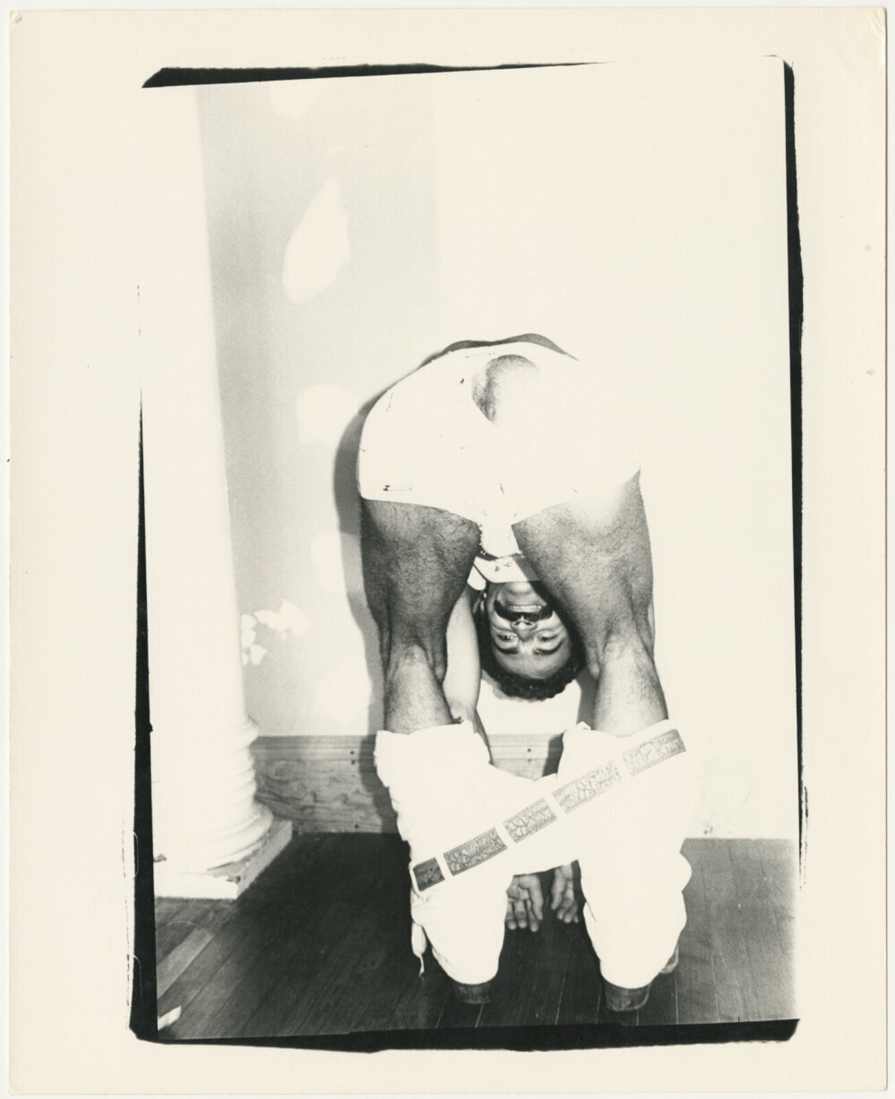 A black and white photo of a man doing a handstand.