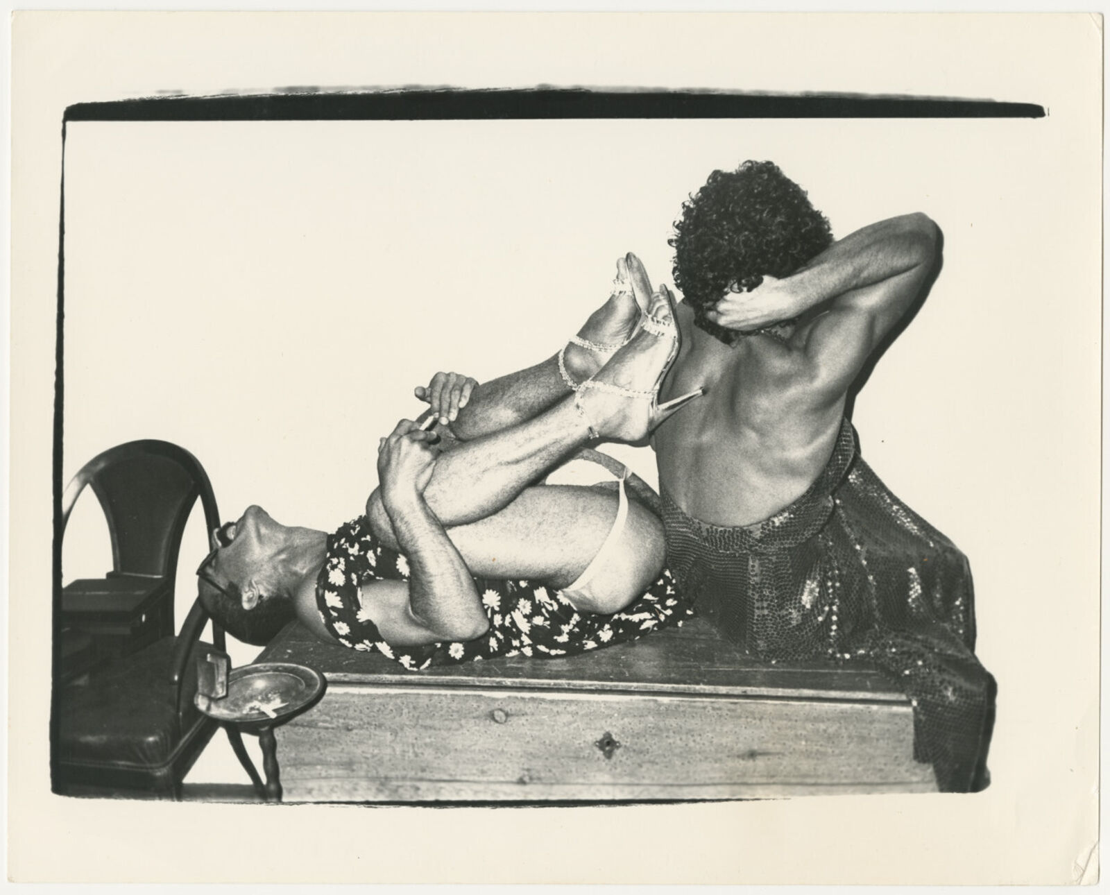 A black and white photo of a man and a woman laying on a bench.