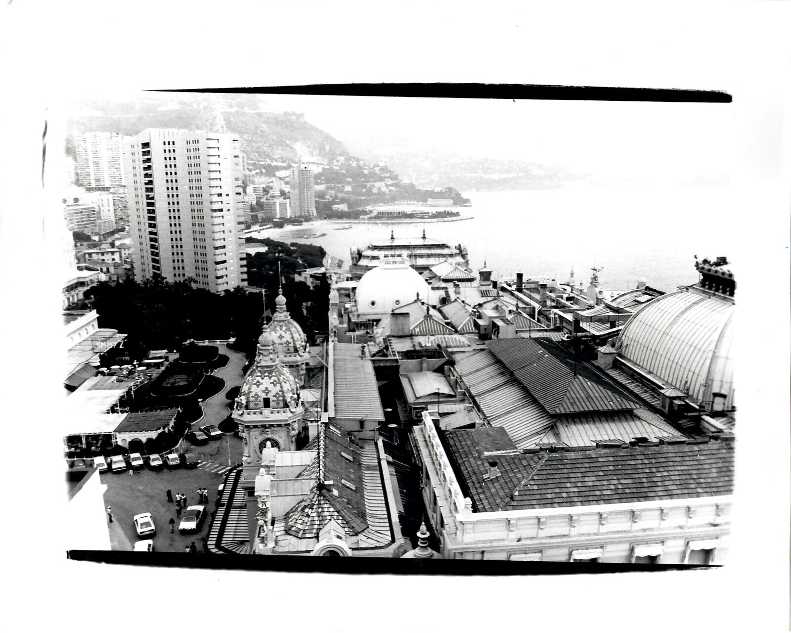 A black and white photo of a view of a city from the top of a building.