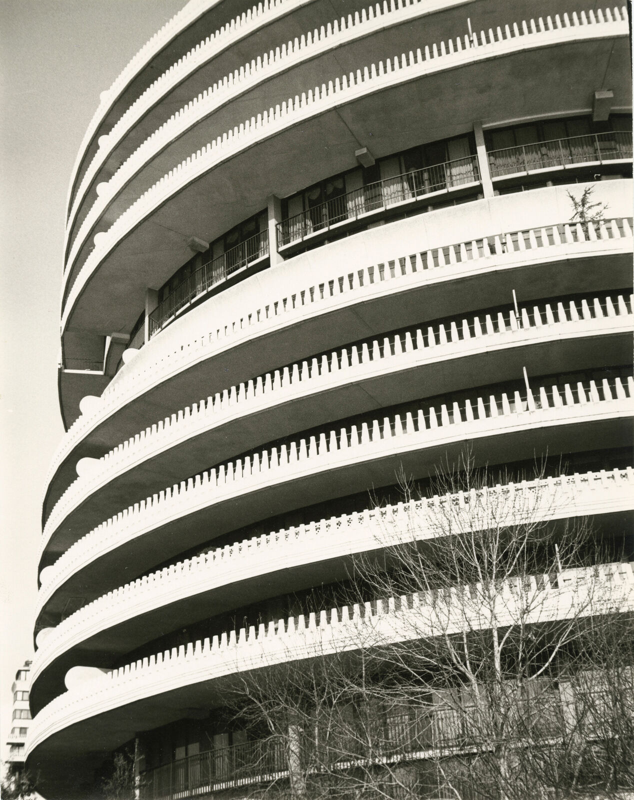 A black and white photo of a tall building with balconies.