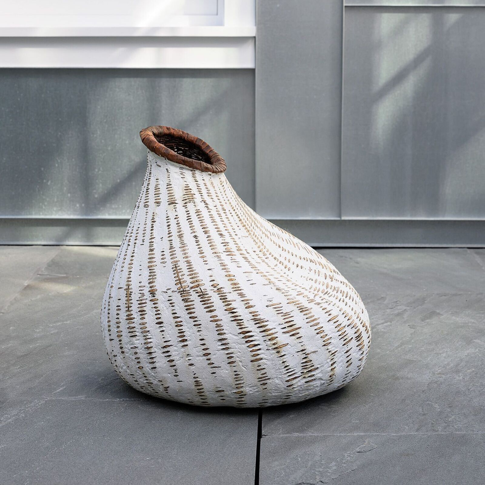 A white vase sitting on top of a wooden floor.