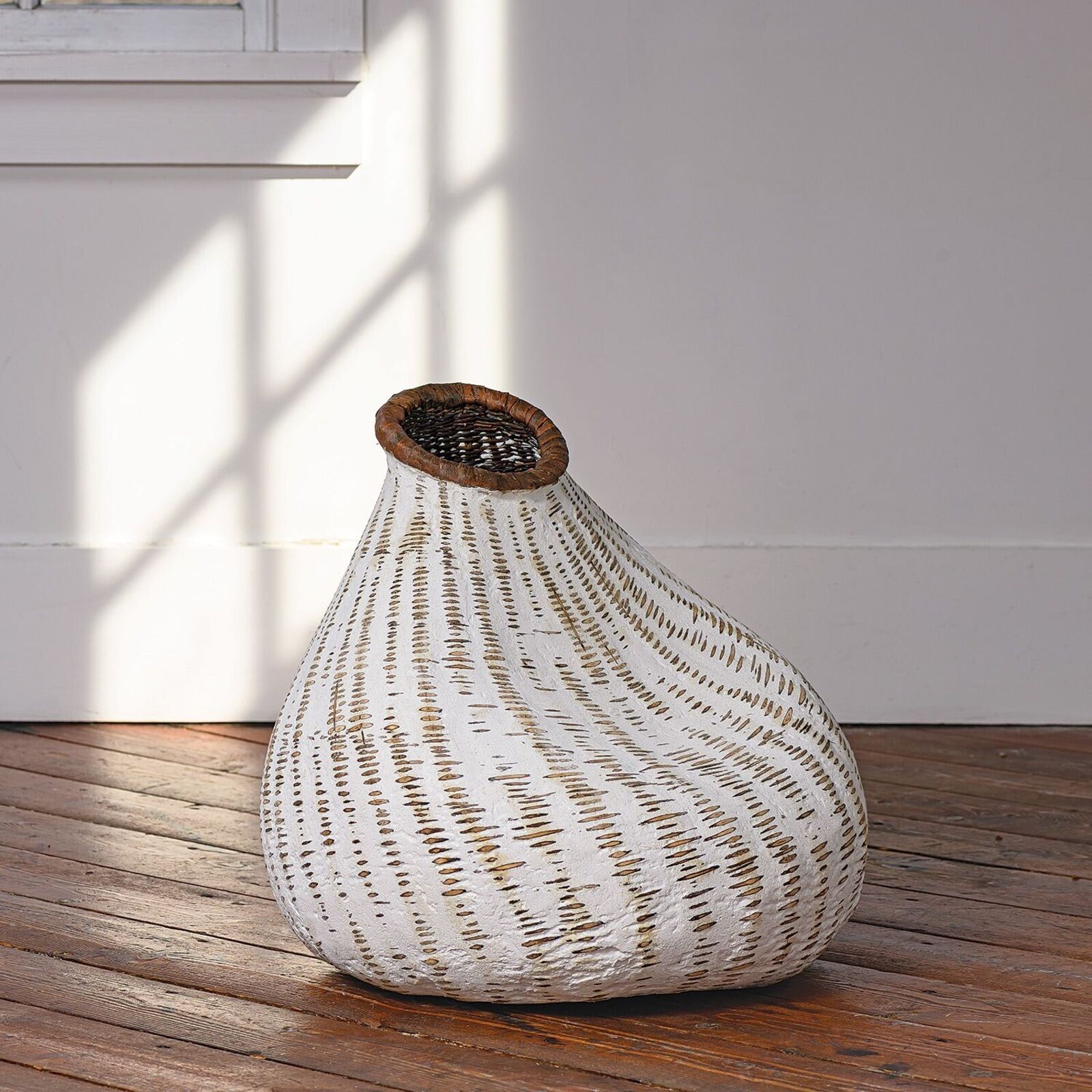 A white vase sitting on top of a wooden floor.