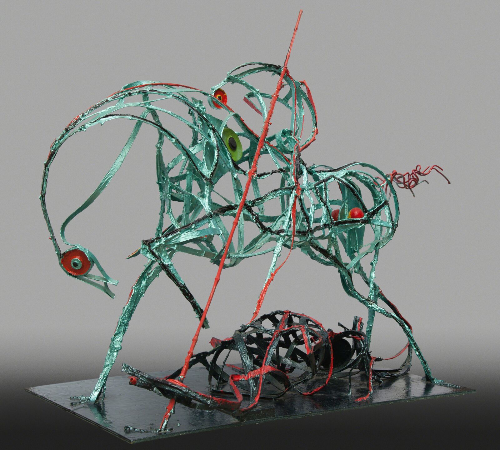 A metal sculpture of a green and red horse on a metal base.