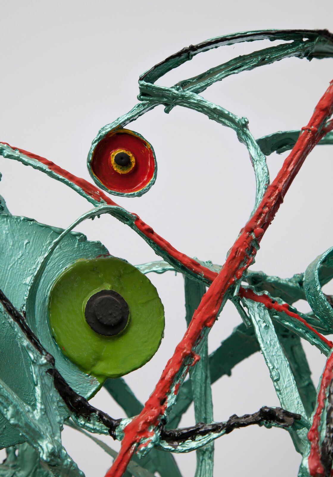A metal sculpture of a green and red horse on a metal base.