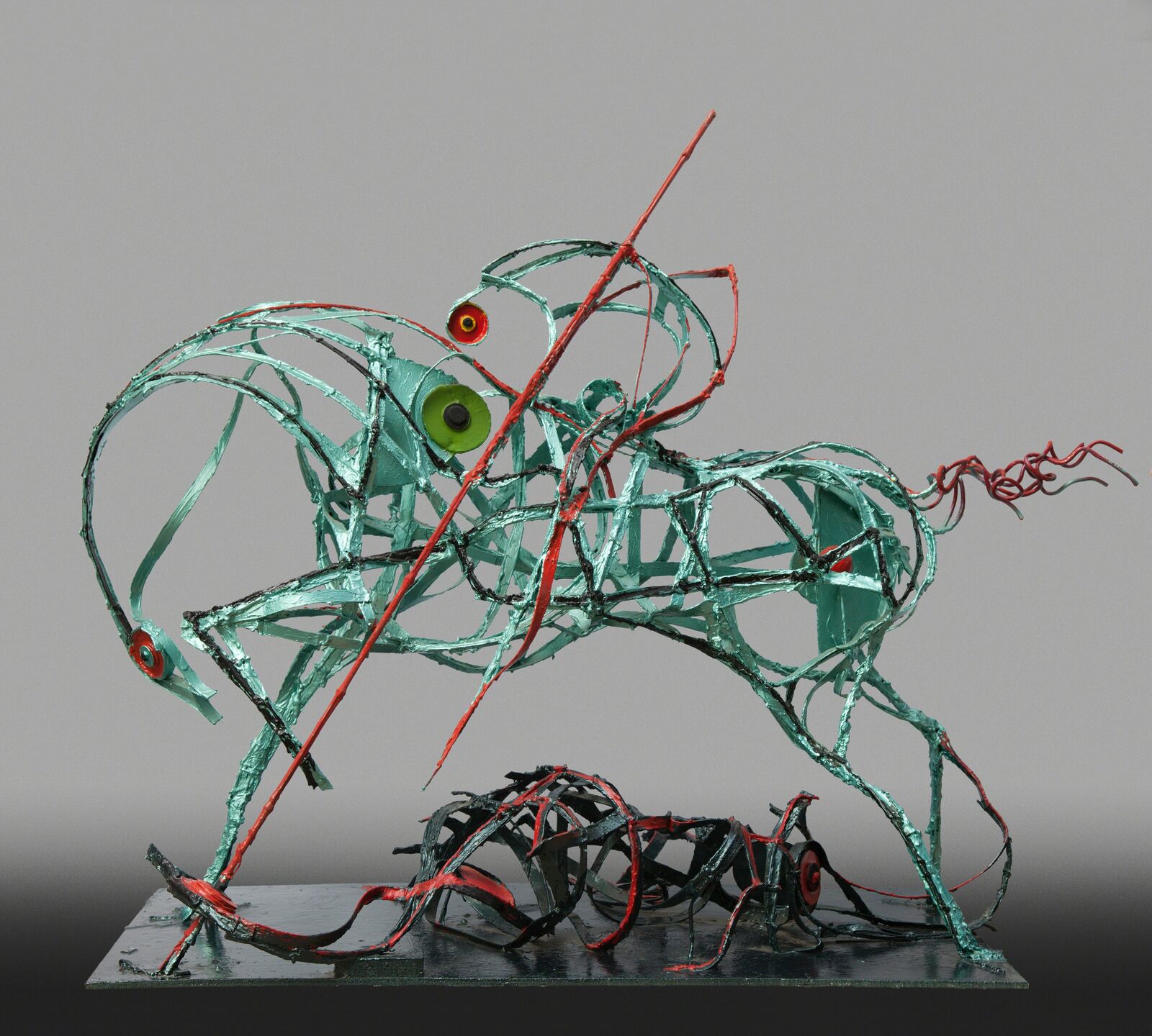 A metal sculpture of a green and red horse on a metal base.