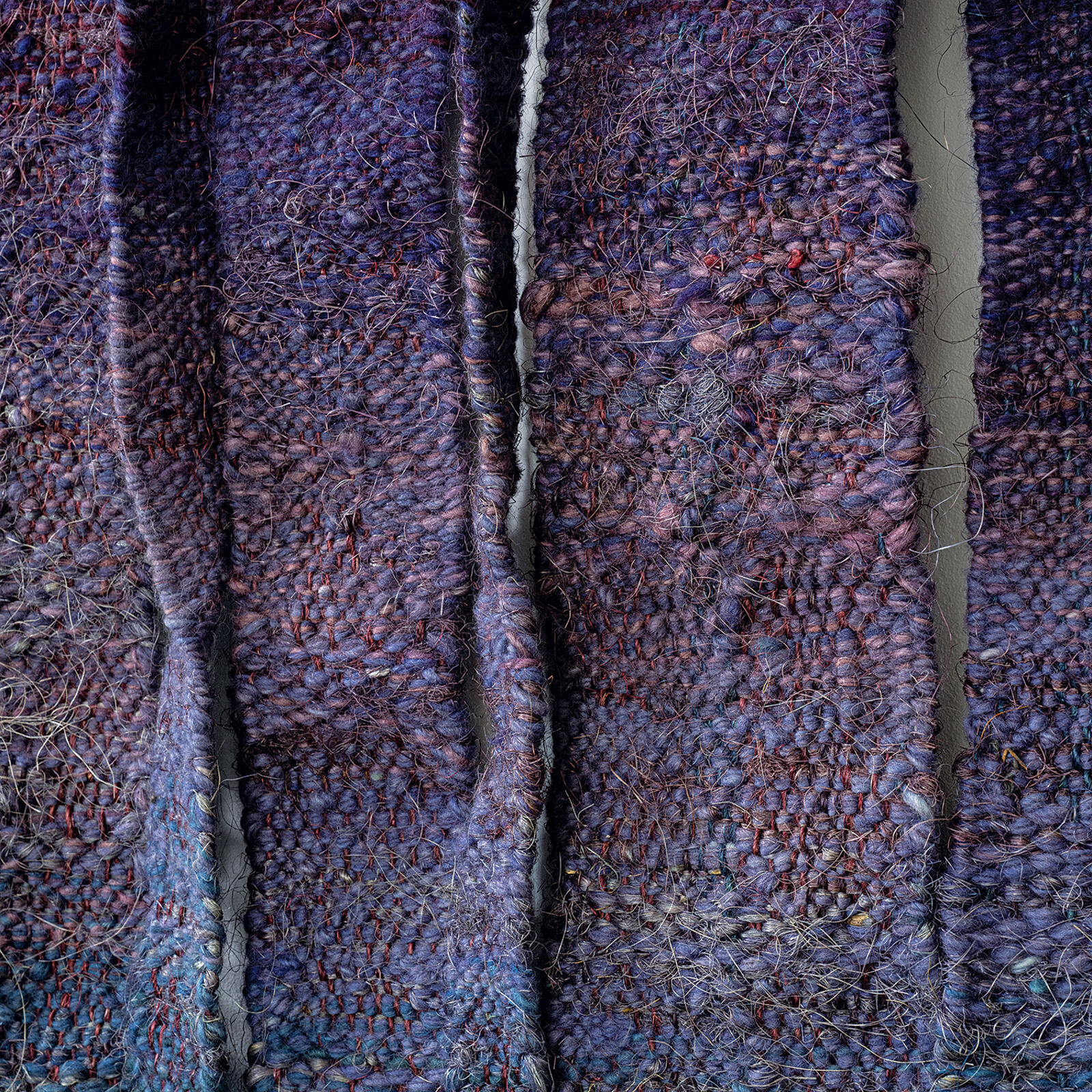 A blue and purple wall hanging on a white wall.