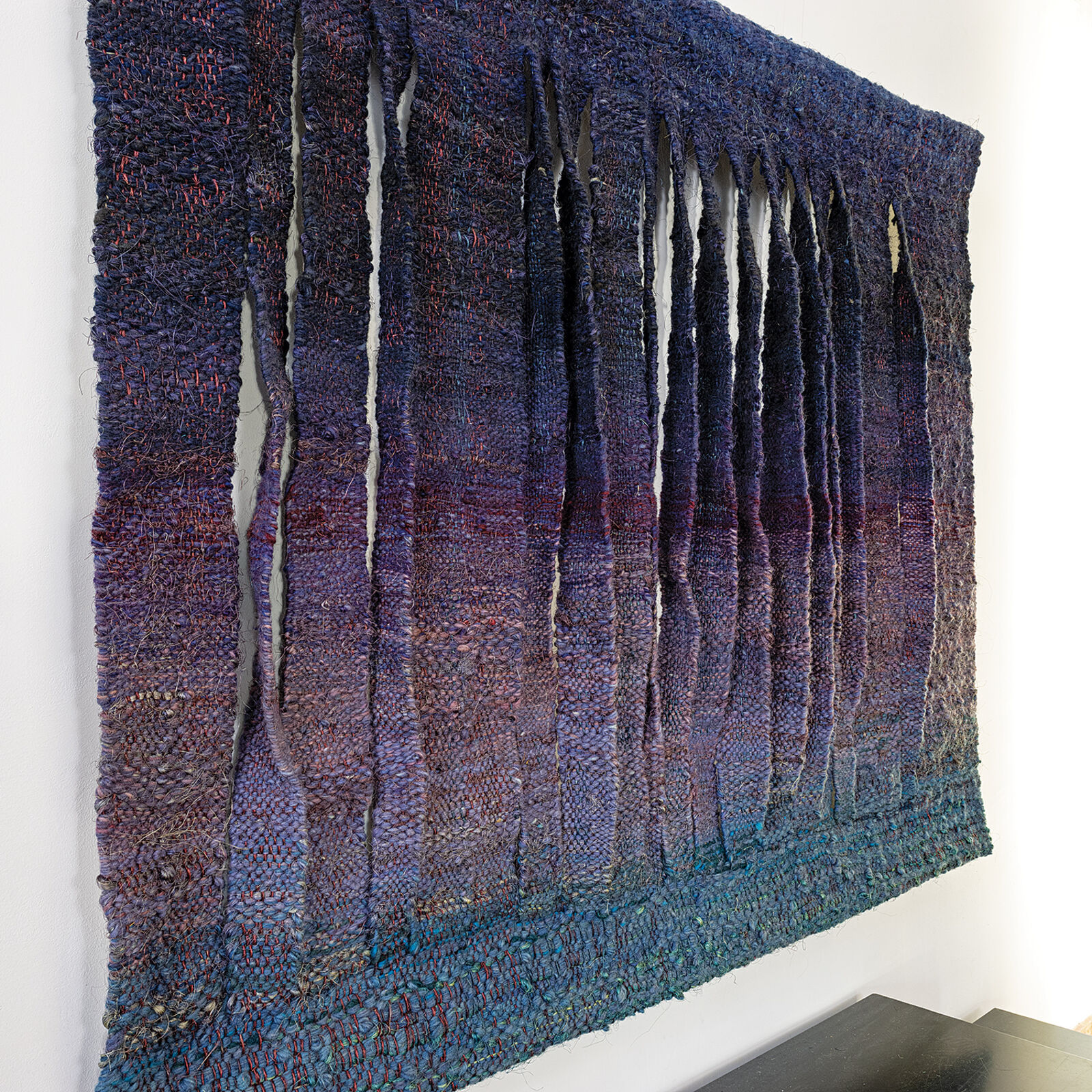 A blue and purple wall hanging on a white wall.