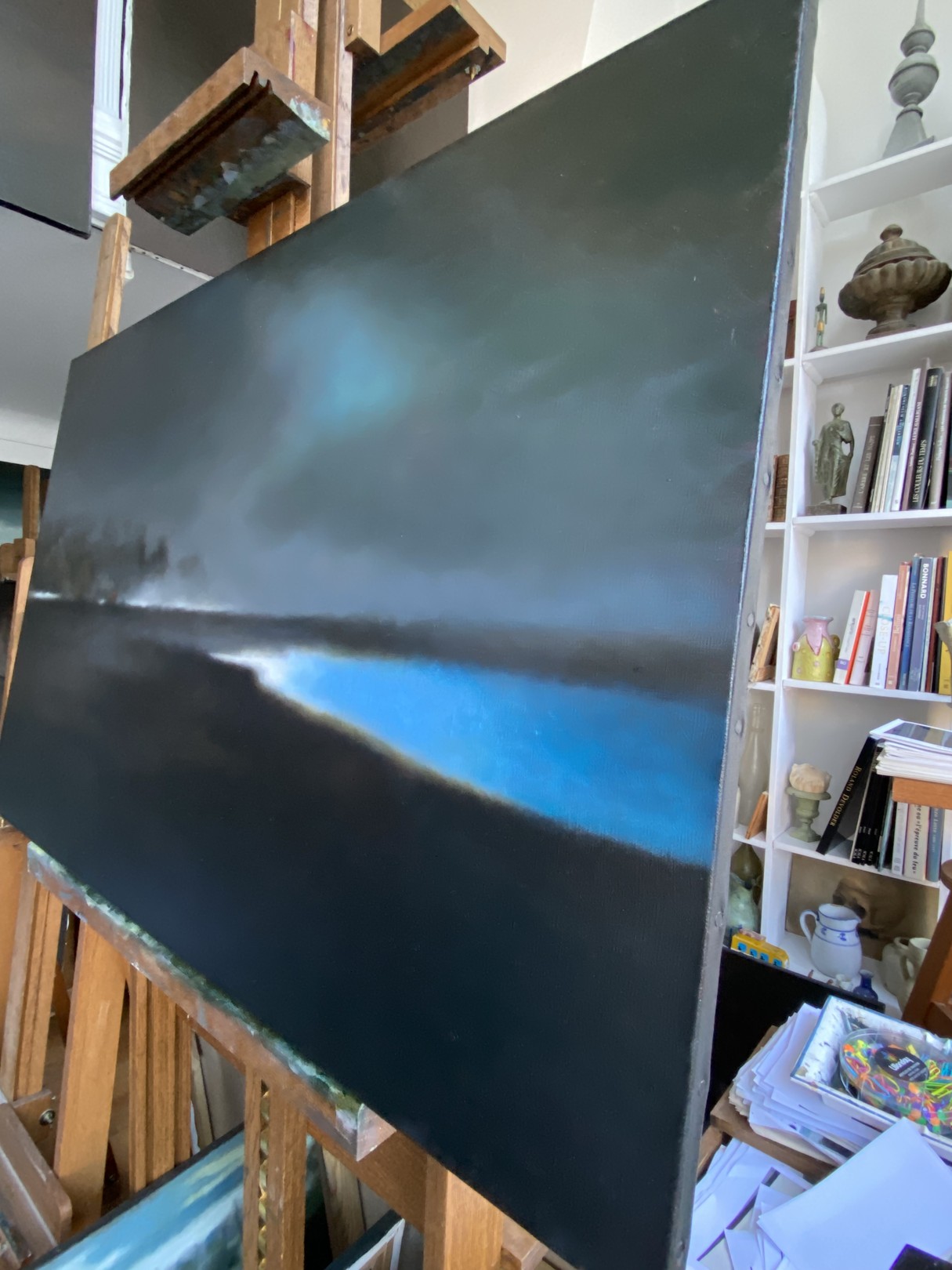 A painting of a dark sky over a body of water.