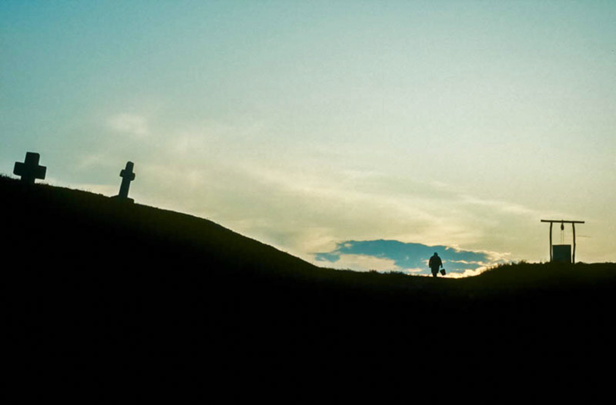 A person walking up a hill with three crosses on it.
