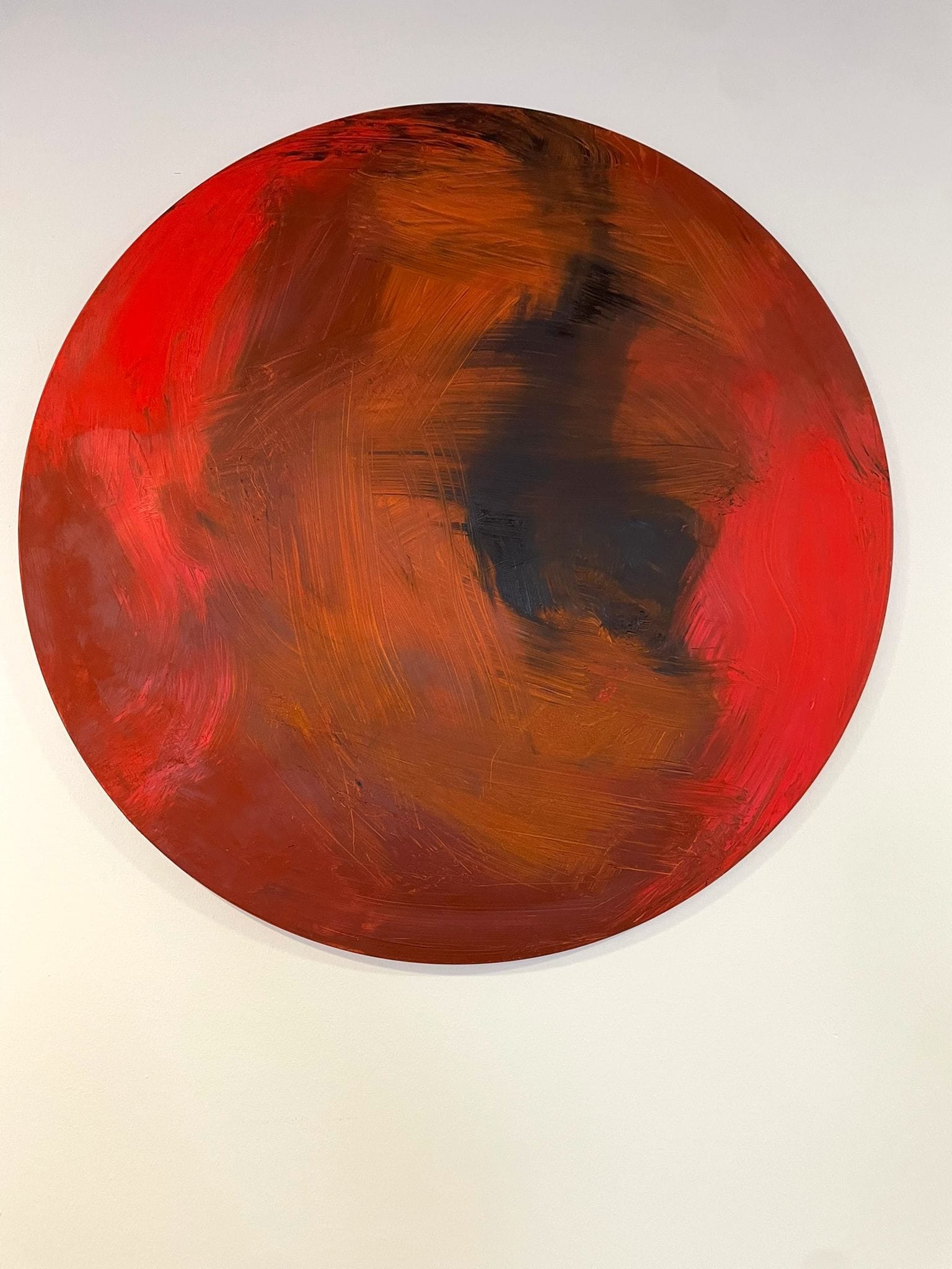 A bold abstract painting featuring a large red circle with expressive brushstrokes and a dark central form.
